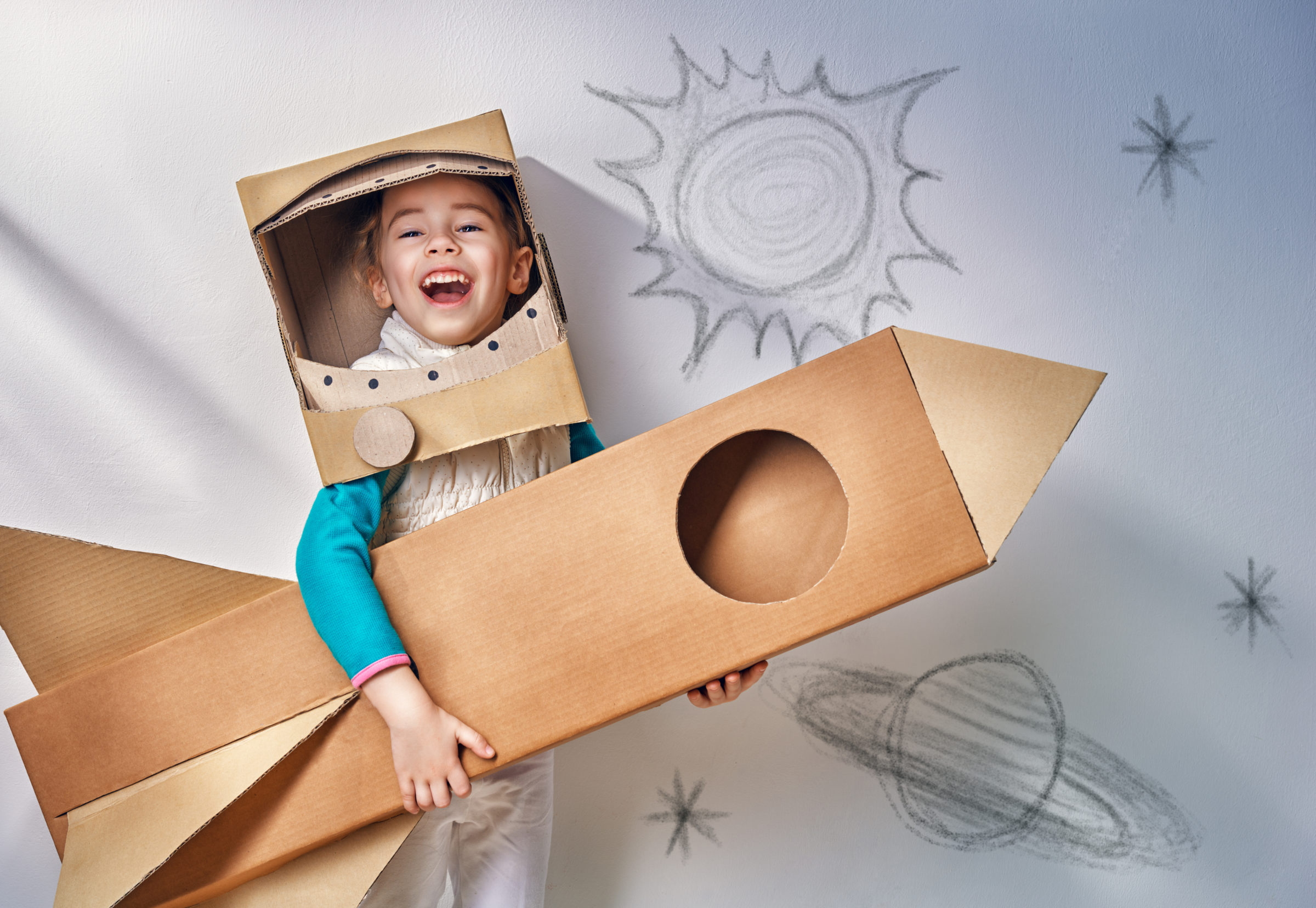 Child dressed in cardboard astronaut costume and rocket