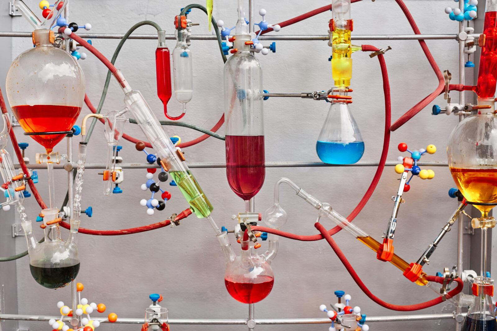 Glass test tubes with colorful viscous liquid isolated over gray background in chemical laboratory, closeup. Checking the quality of petroleum products refining concept.