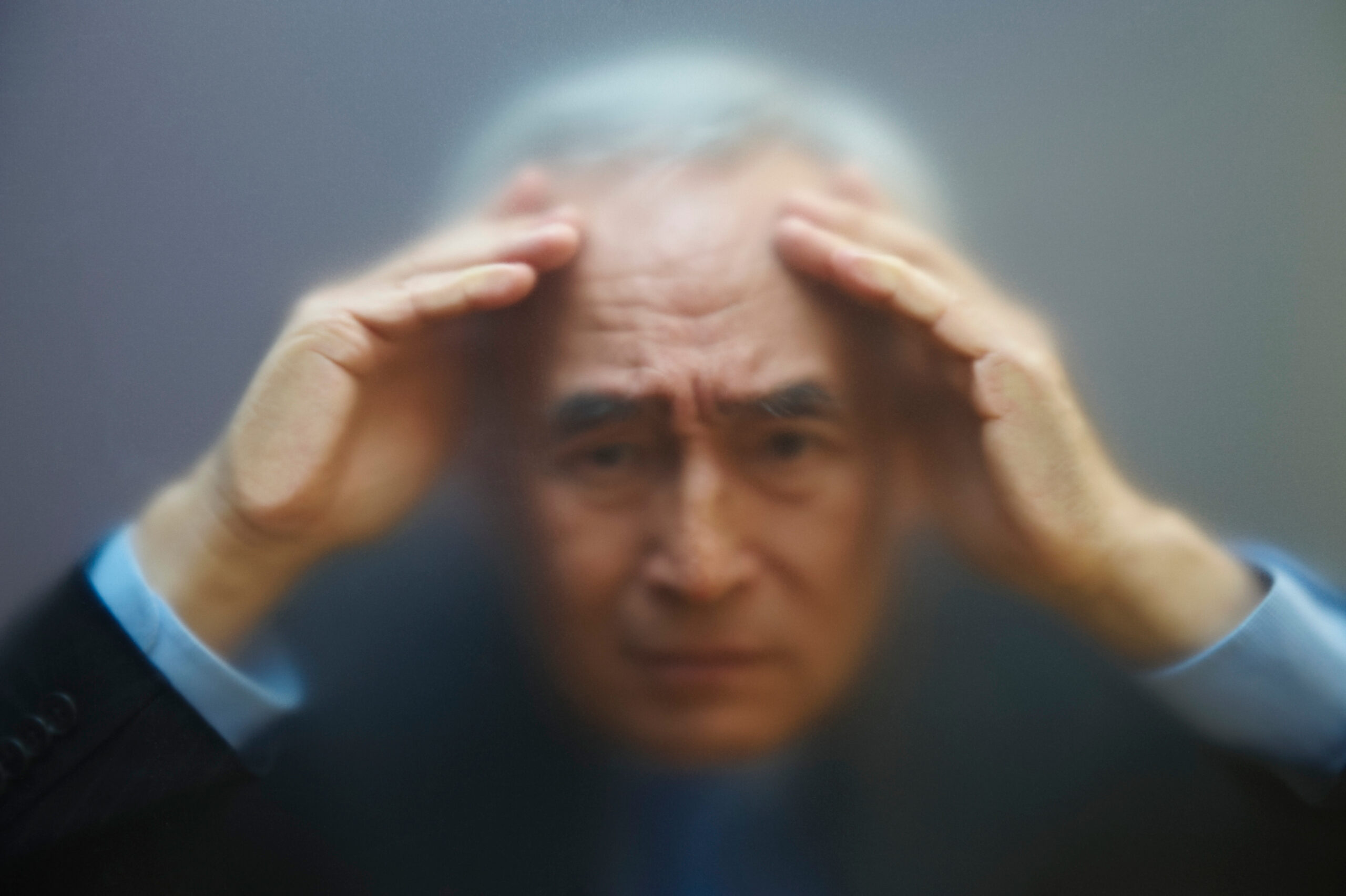 Senior man peering through frosted glass