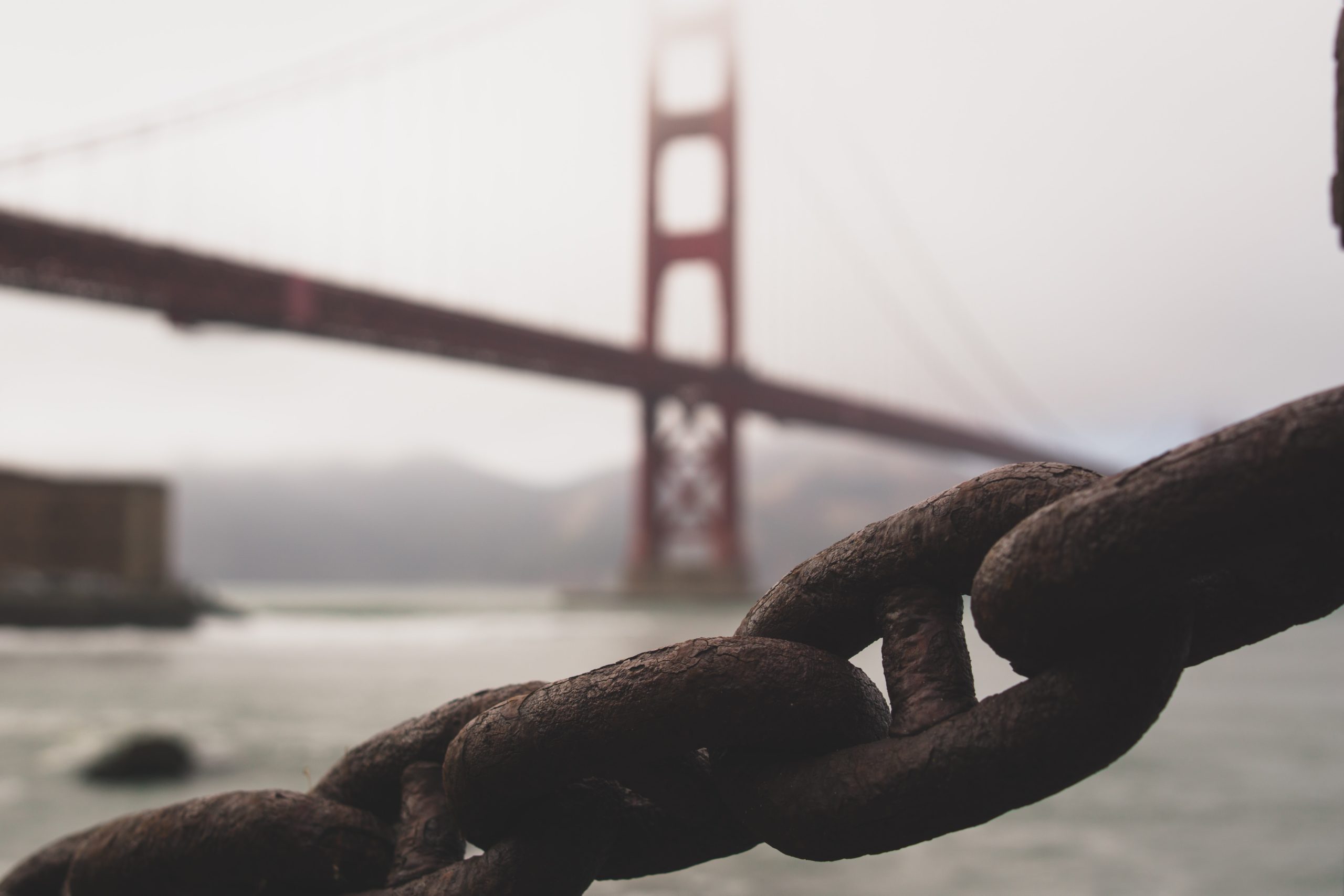 Photo of Golden Gate Bridge in background, large chain in front