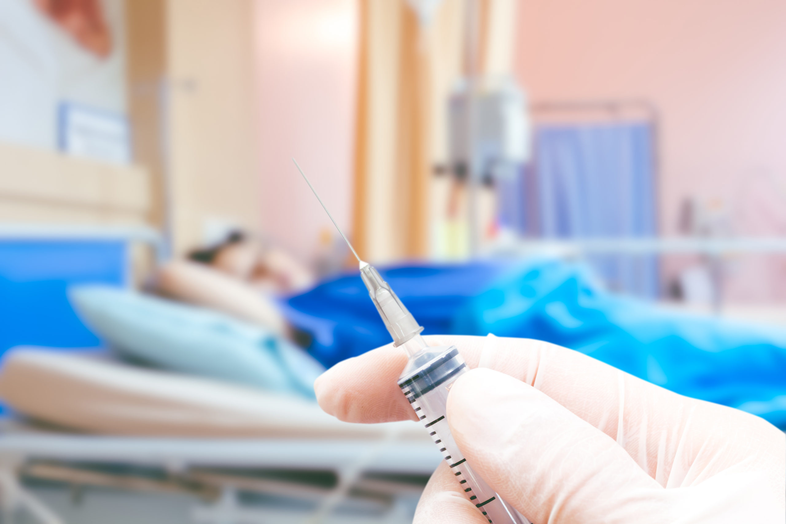 Medical syringe in the doctor's hands on the patient's in room h