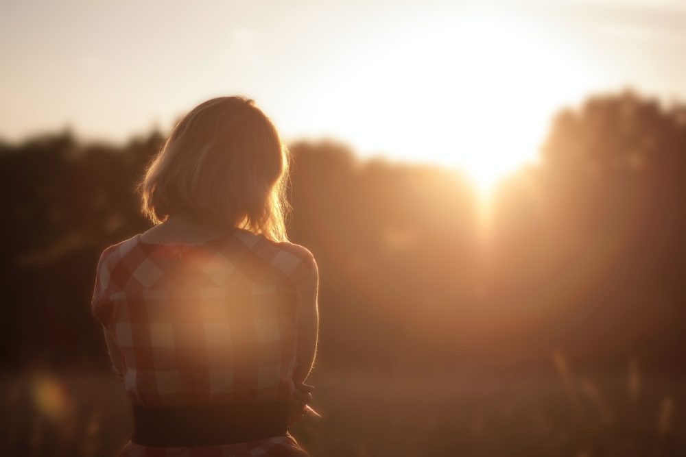 Woman contemplates sunrise.