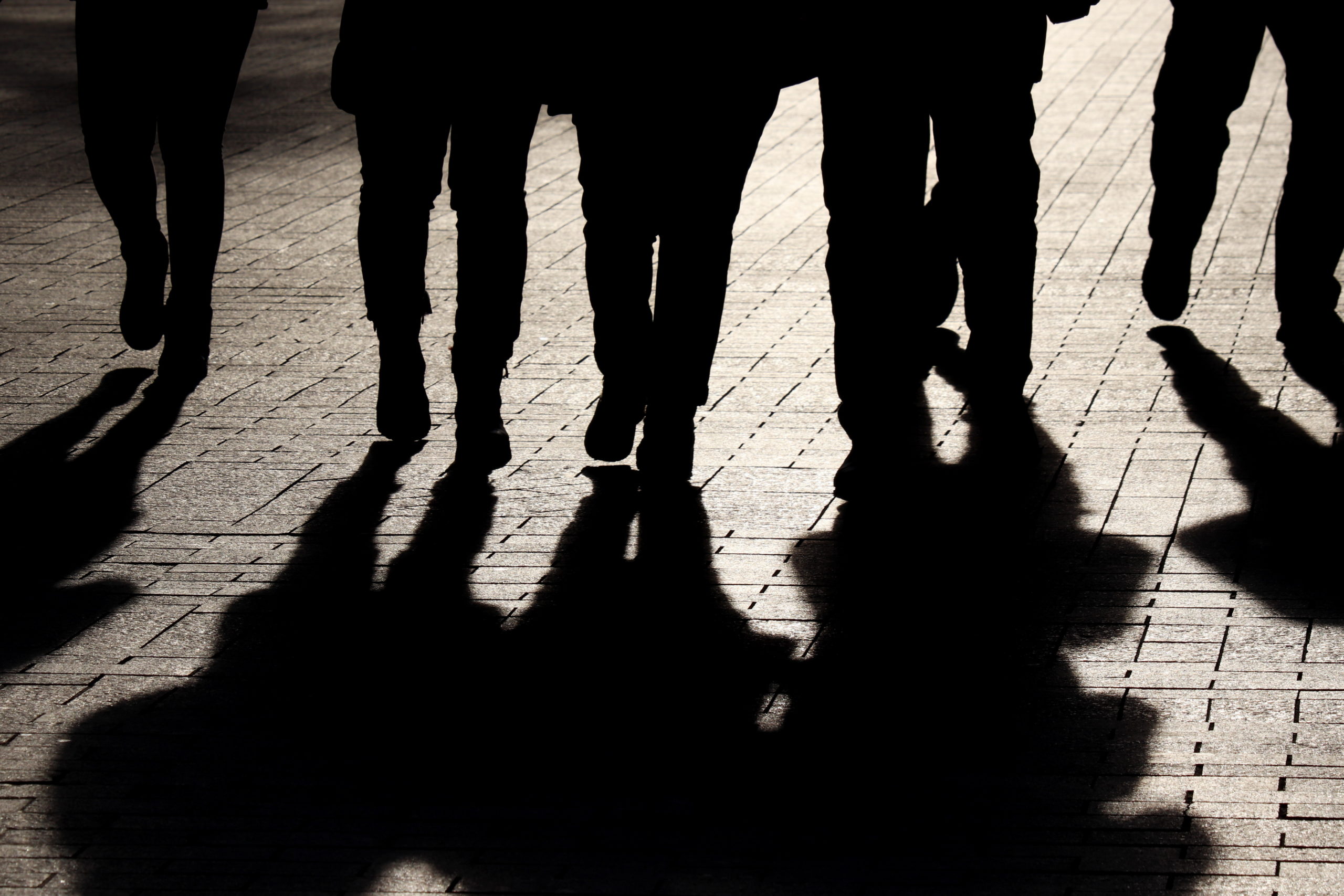 Silhouettes and shadows of people on the street. Crowd walking down on sidewalk, concept of strangers, crime, society, epidemic, population