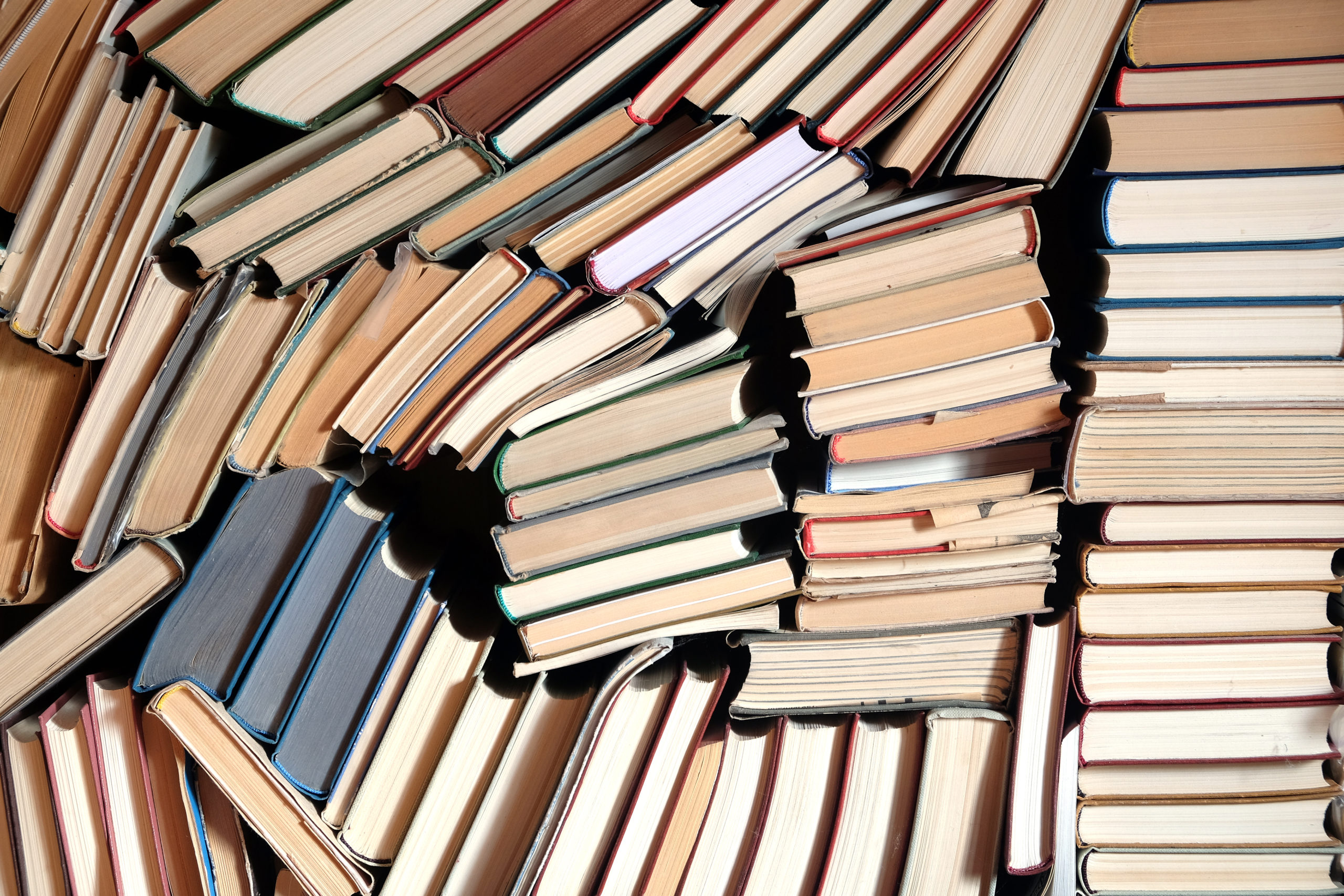 Many assorted old books lays in the stacks as background front view close up