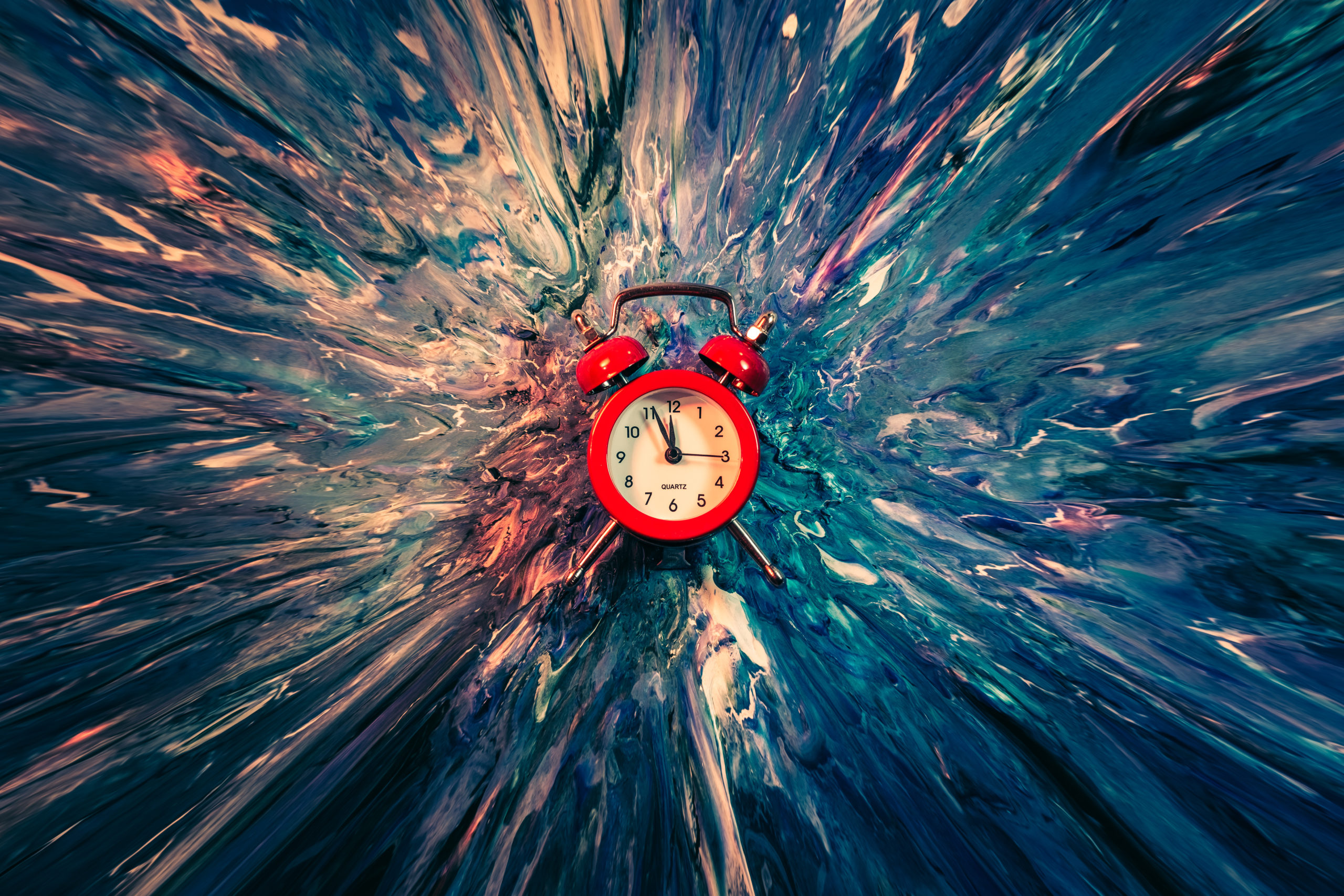 Time flies. Red vintage alarm clock falling down into blue and white paint with splash effect. Abstract art background.