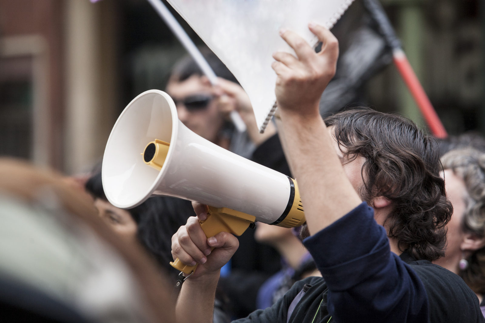 Unidentified young demostrator with megaphone and notebook protesting against austerity cuts