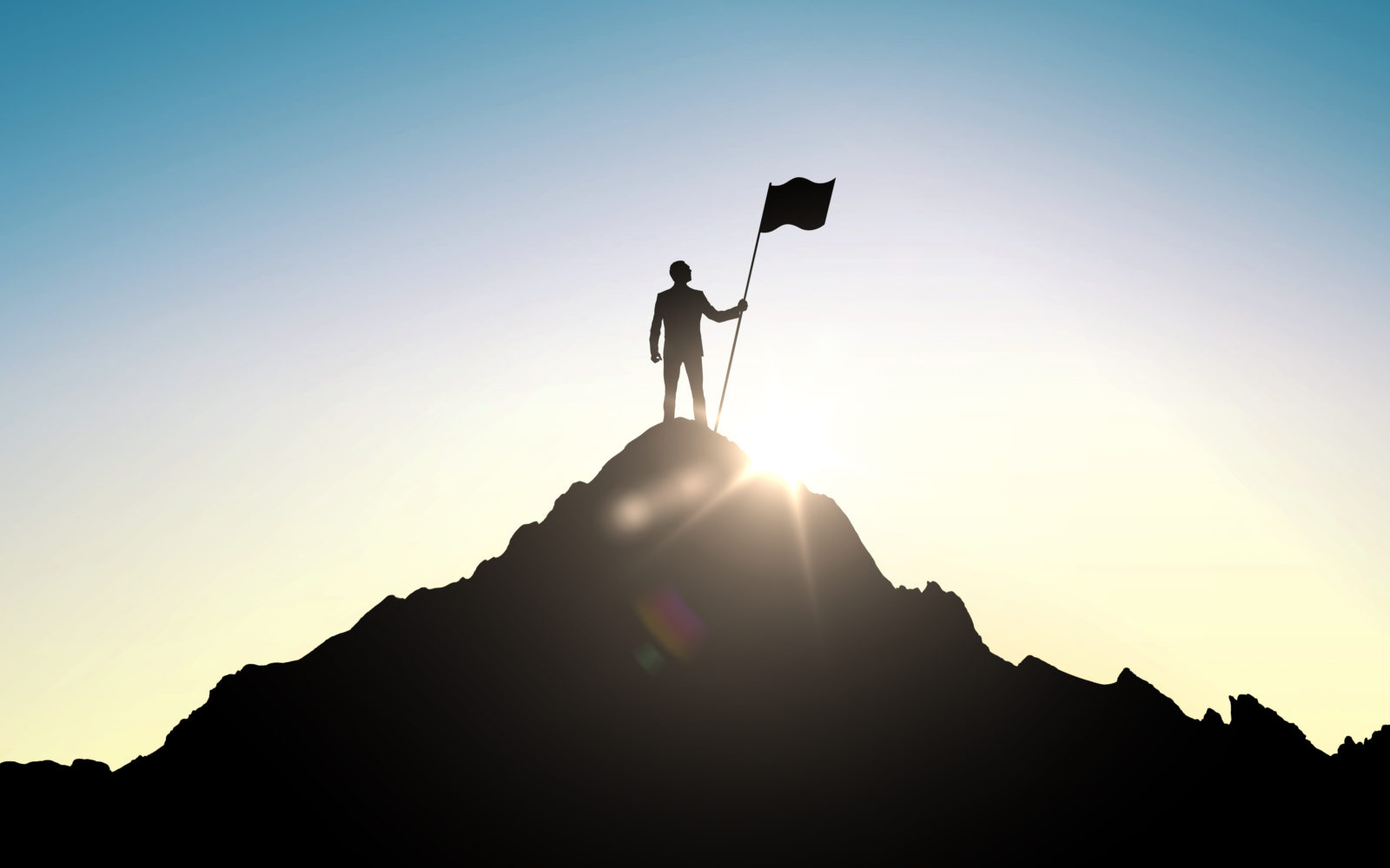 silhouette of businessman with flag on mountain