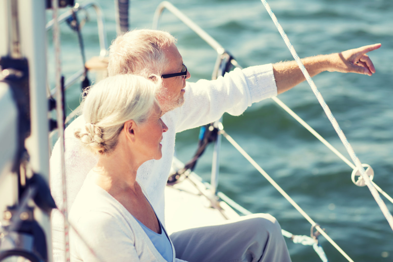 happy senior couple on sail boat or yacht in sea