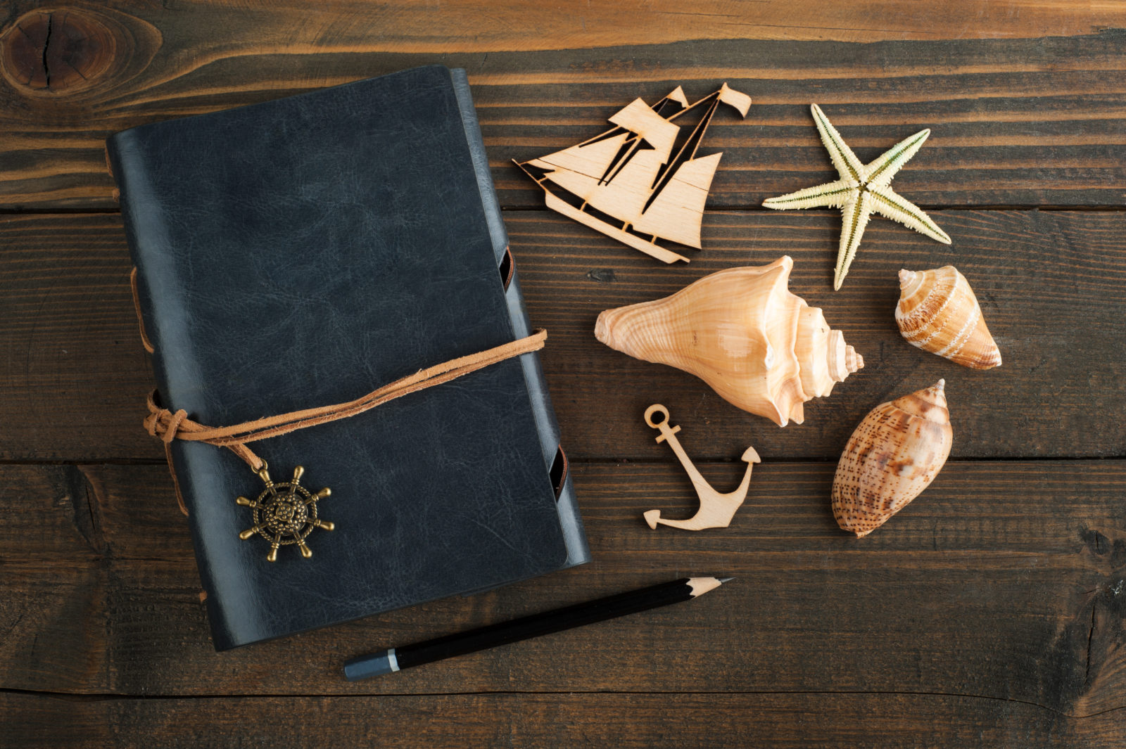 Notebook, sea shells and wooden ship