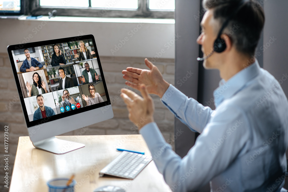 Virtuak business meeting online. Successful businessman is negotiating with multiracial business partners on a video conference using a computer while sitting at his workplace