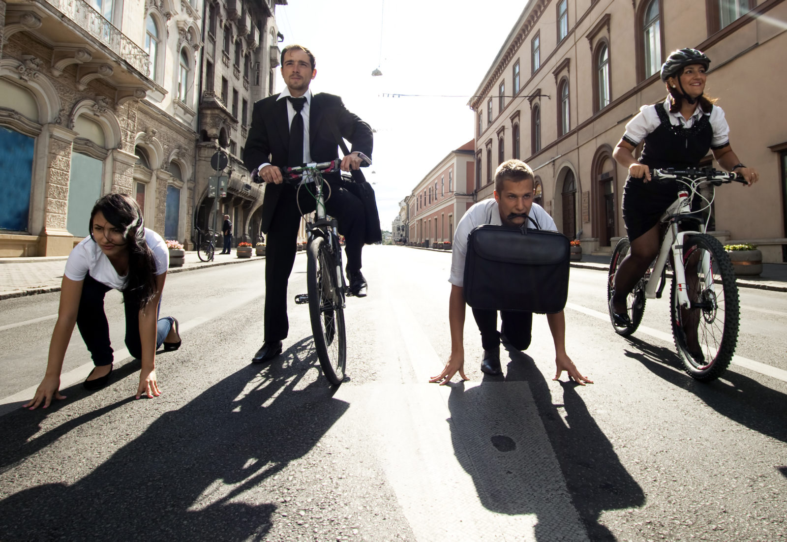Businesspeople competing with bicycles and running in the city