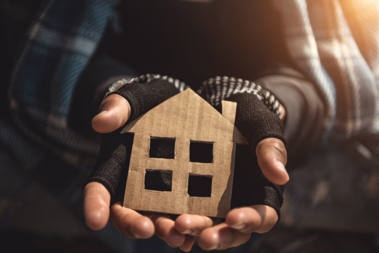 Hands of Homelessness Poor man holding the paper house hope to have family home and warm home