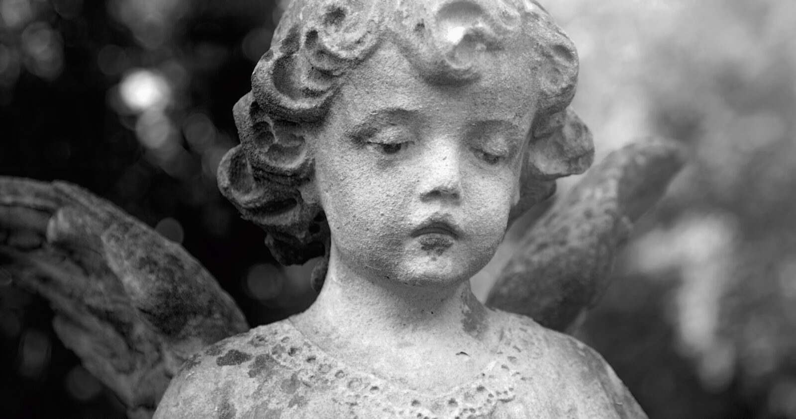 Vintage image of a sad angel against the background of leaves