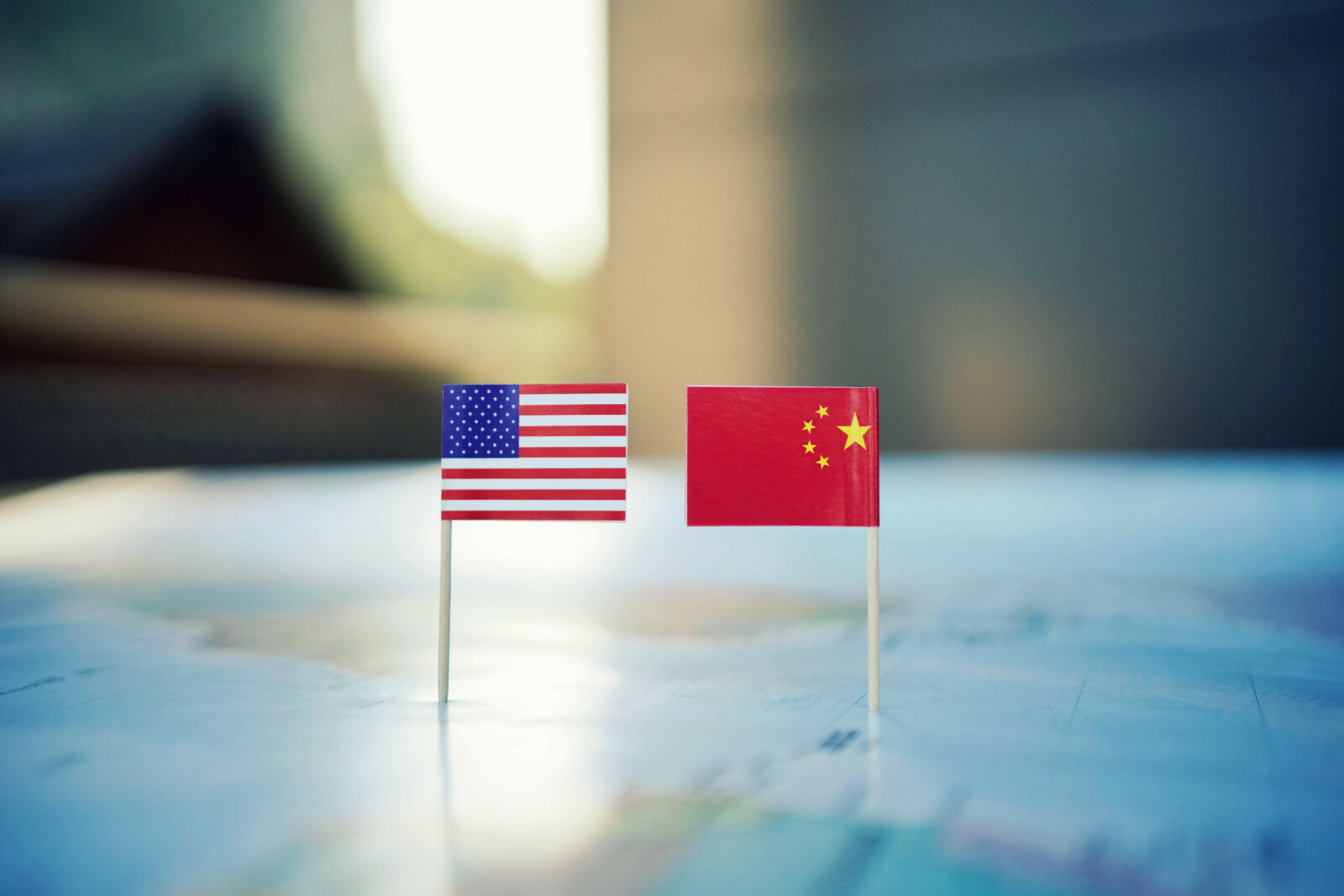 Small flags of USA and China next to each other on a world map representing bilateral relations.