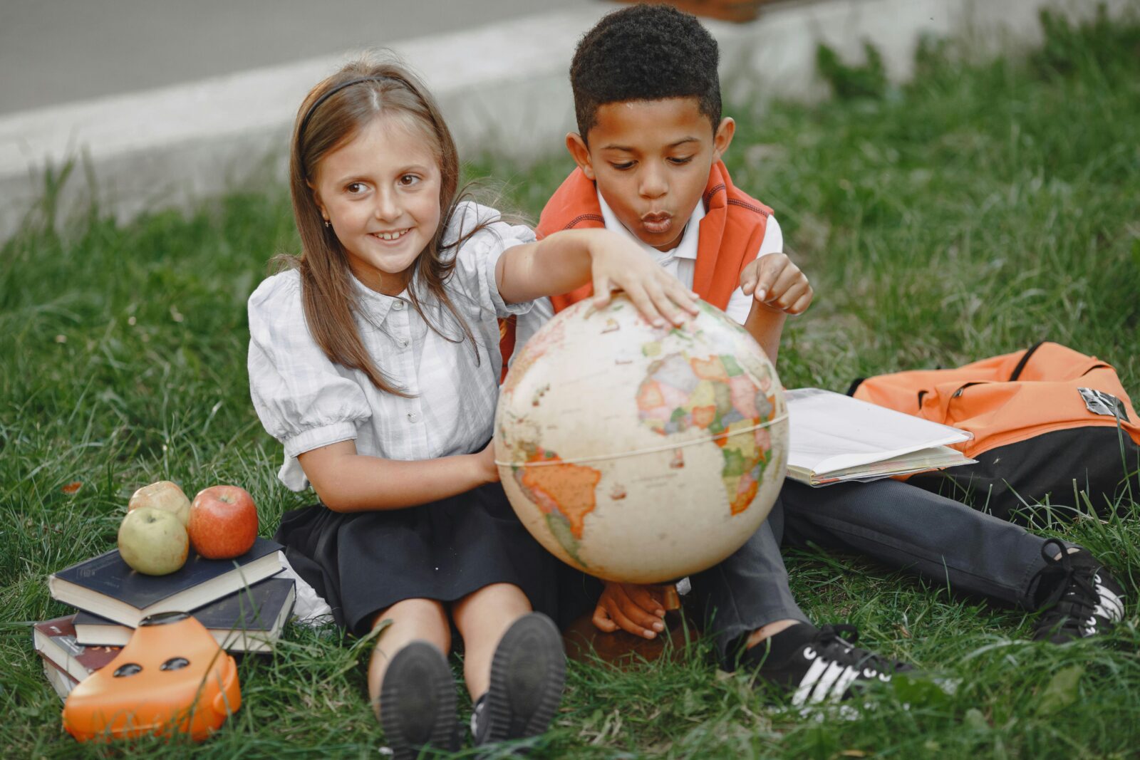 Young students sitting on green grass field