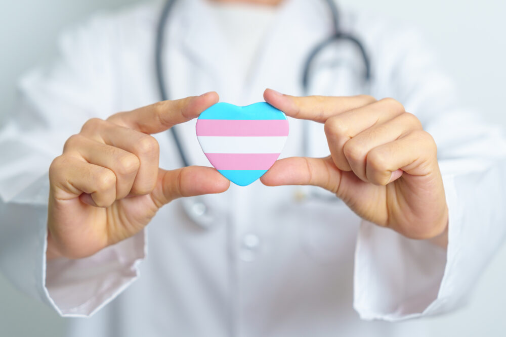 Transgender Day and LGBT pride month, LGBTQ+ or LGBTQIA+ concept. Doctor holding blue, pink and white heart shape for Lesbian, Gay, Bisexual, Transgender, Queer and Pansexual community