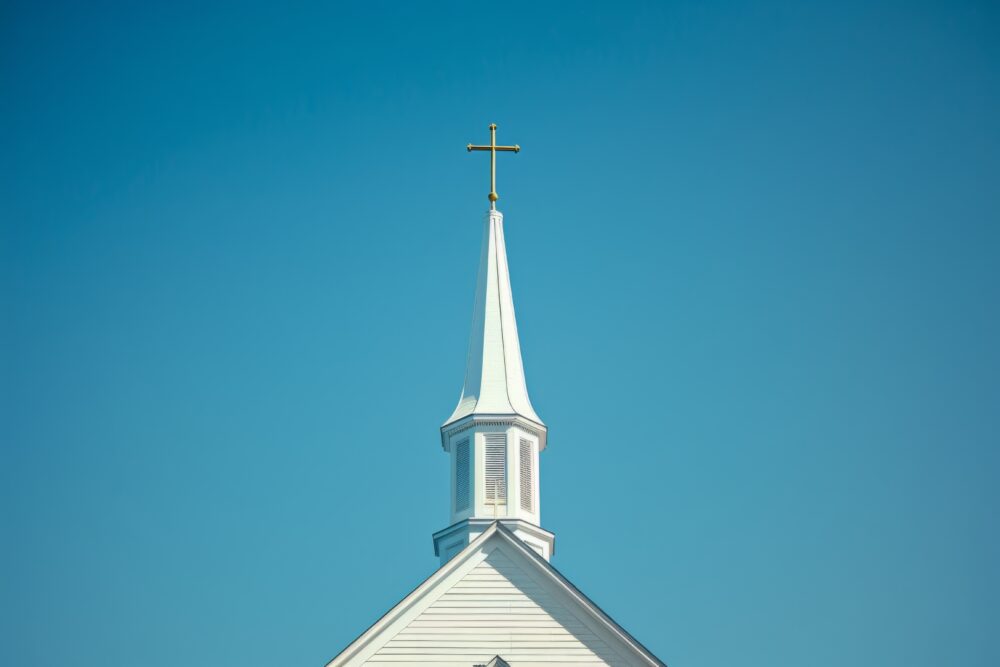 Photo of a church steeple with a cross on top, minimalistic and simple with a clear blue sky background in soft natural light with sharp focus Generative AI