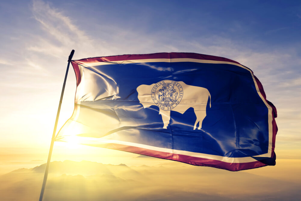 Wyoming state of United States flag waving on the top sunrise mist fog