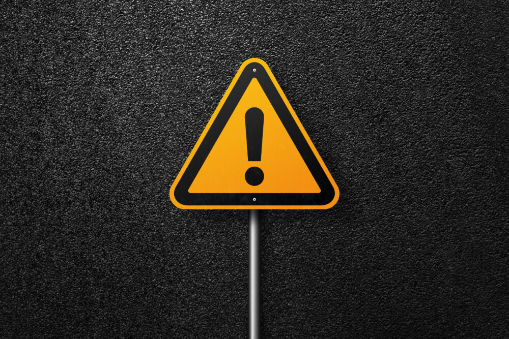 Road sign triangular shape with exclamation mark on a background of asphalt. The texture of the tarmac, top view.
