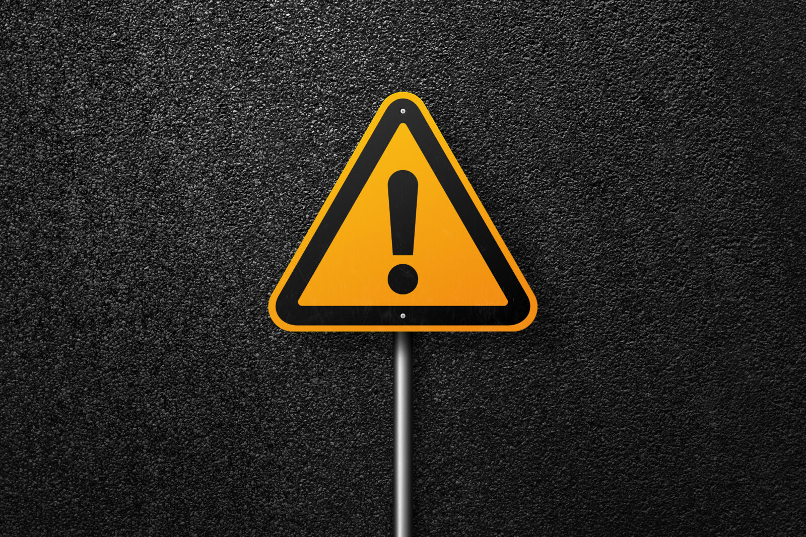 Road sign triangular shape with exclamation mark on a background of asphalt. The texture of the tarmac, top view.