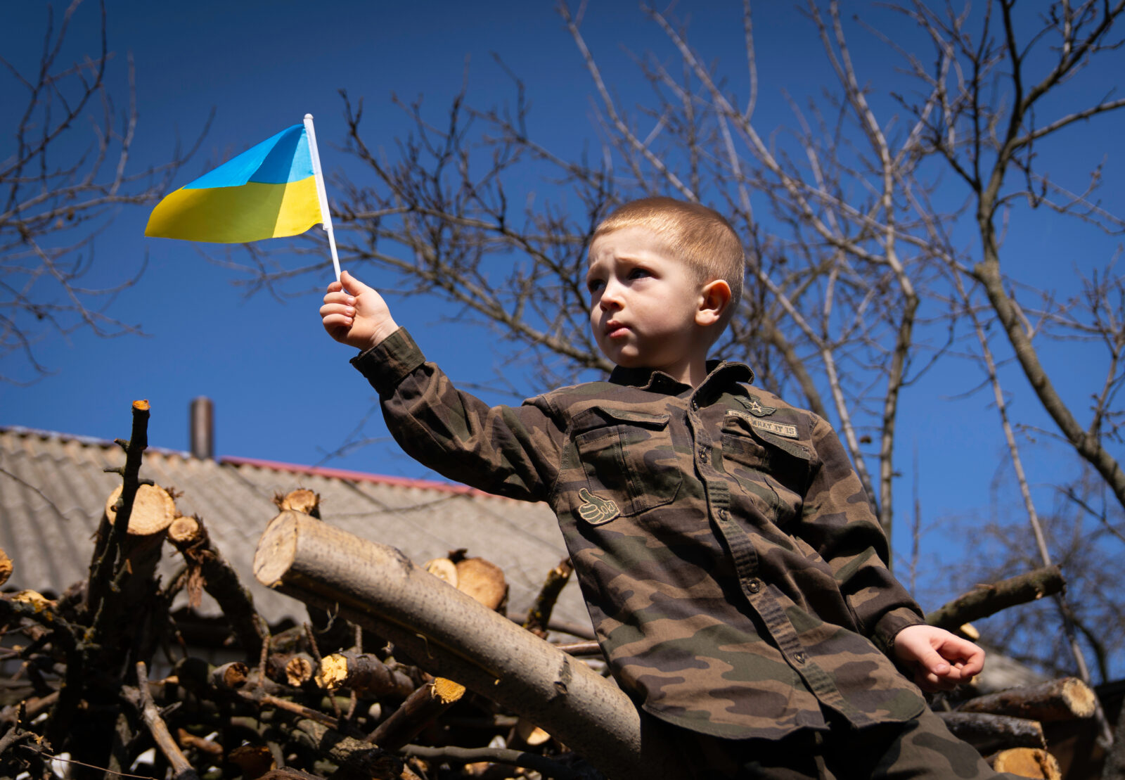 The child holds in his hands a small flag of Ukraine in the hope of peace. Save Ukraine