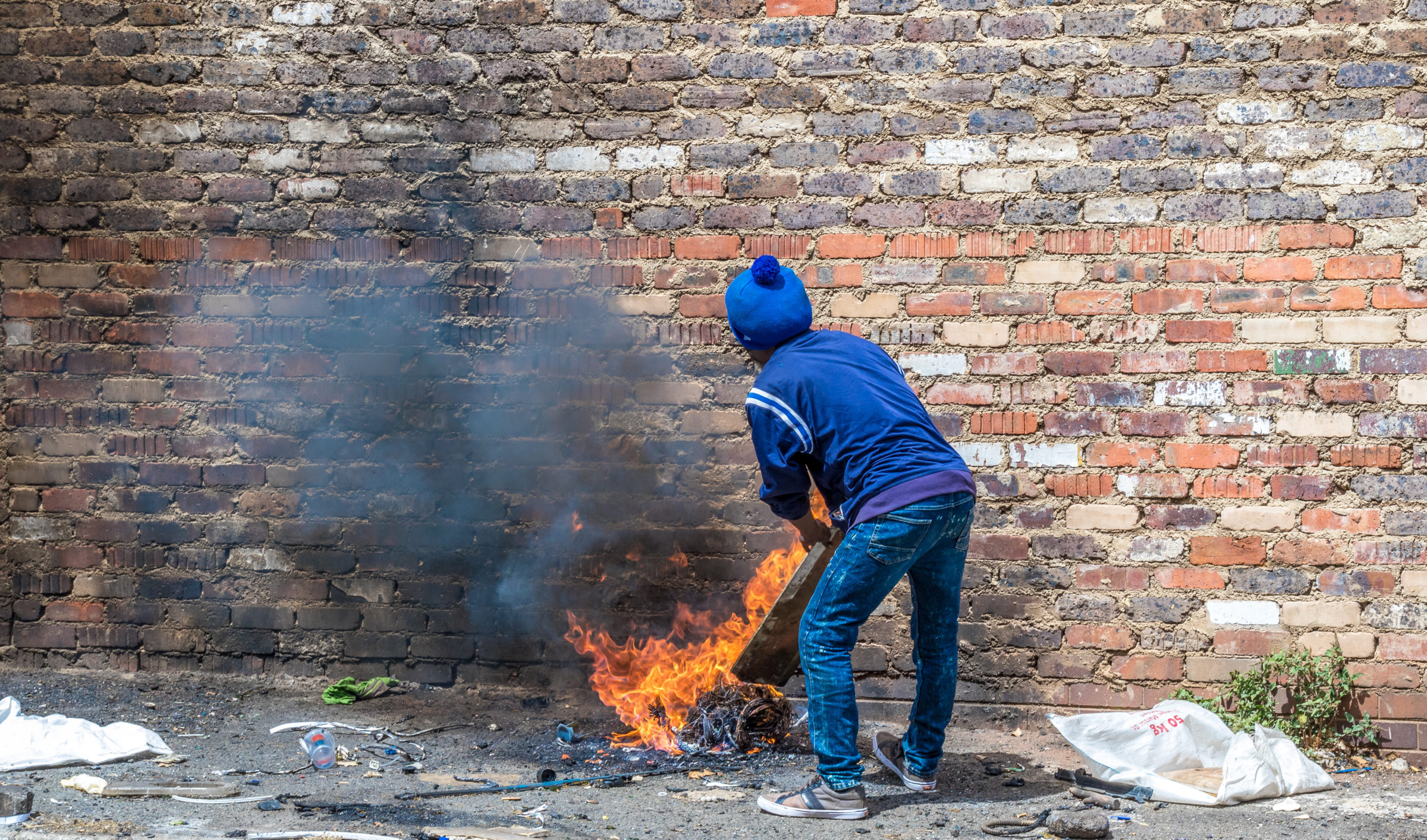 A homeless man in making a fire from rubbish to keep warm image in landscape format with copy space