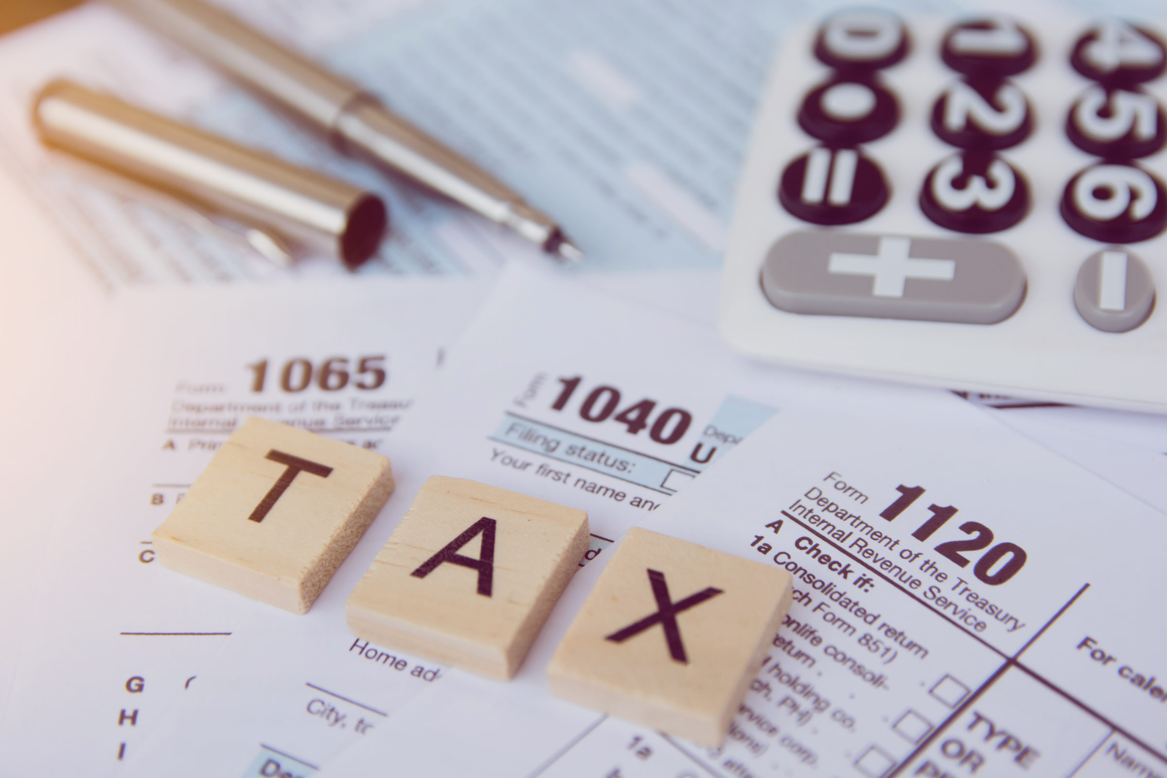 Tax season with wooden alphabet blocks, calculator, pen on 1040 tax form backgrounda