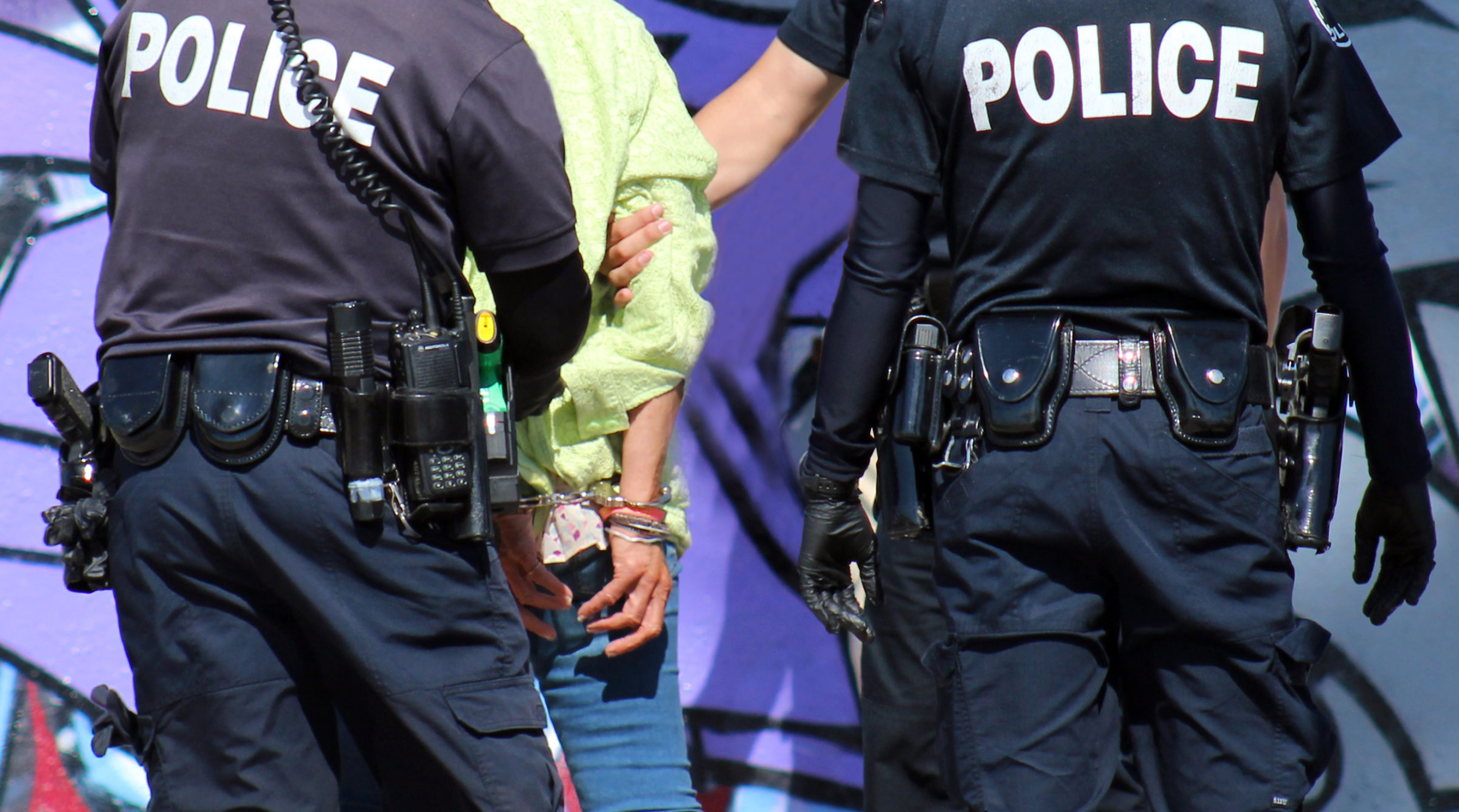 Two police officers arrest and handcuff homeless woman in Venice Beach, Los Angeles, California.