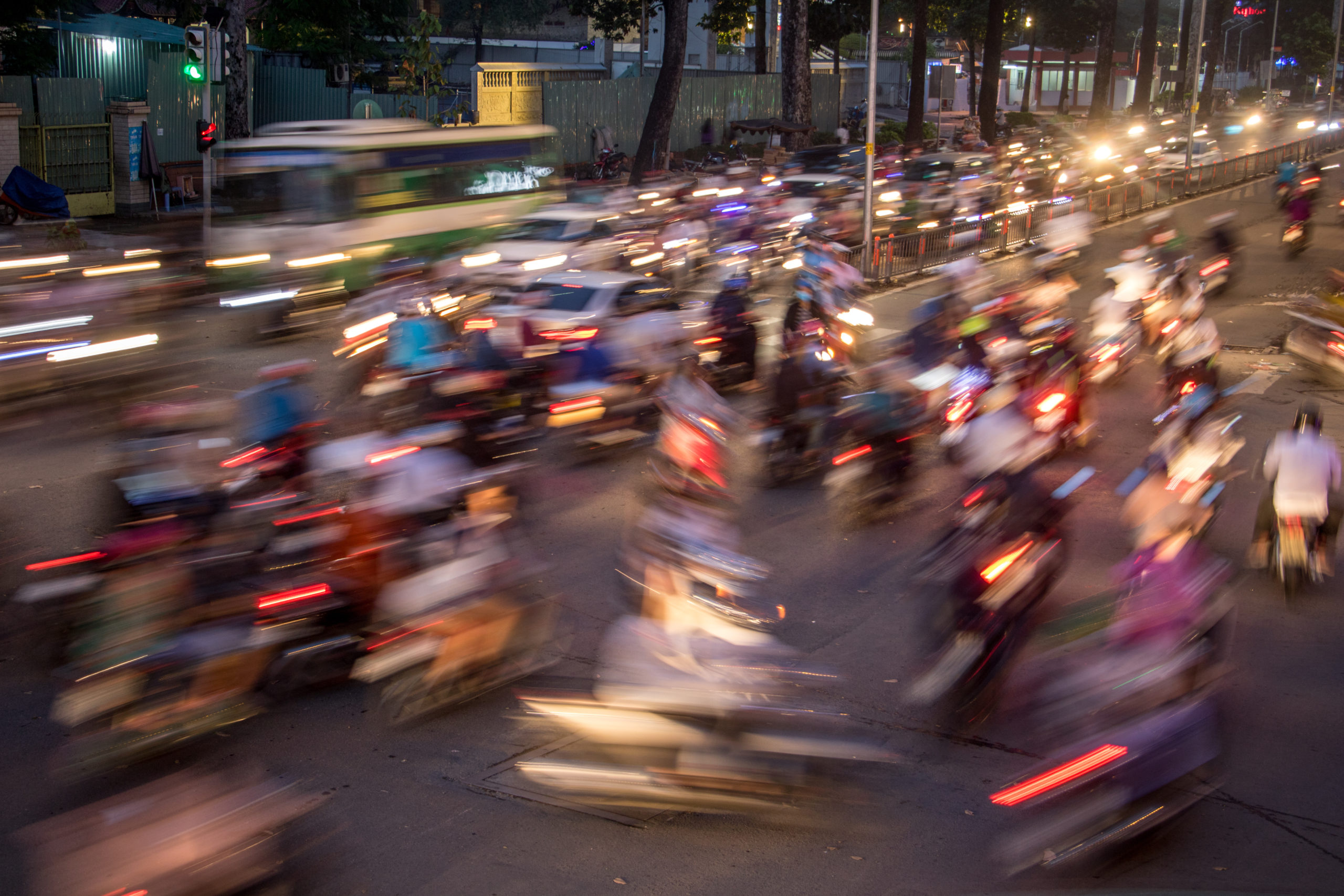 Dense traffic at night intersection with blurred lights passing through motorbikes and vehicles.