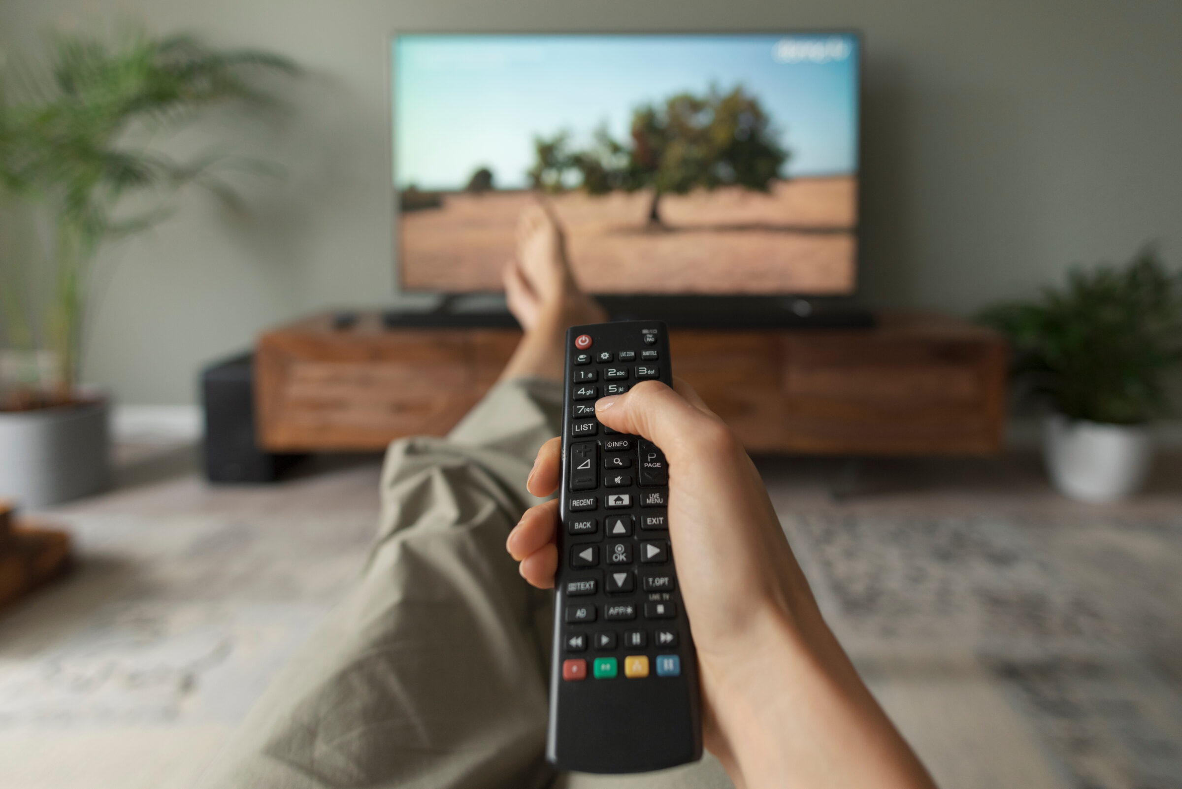 Woman watching TV at home and holding the remote control