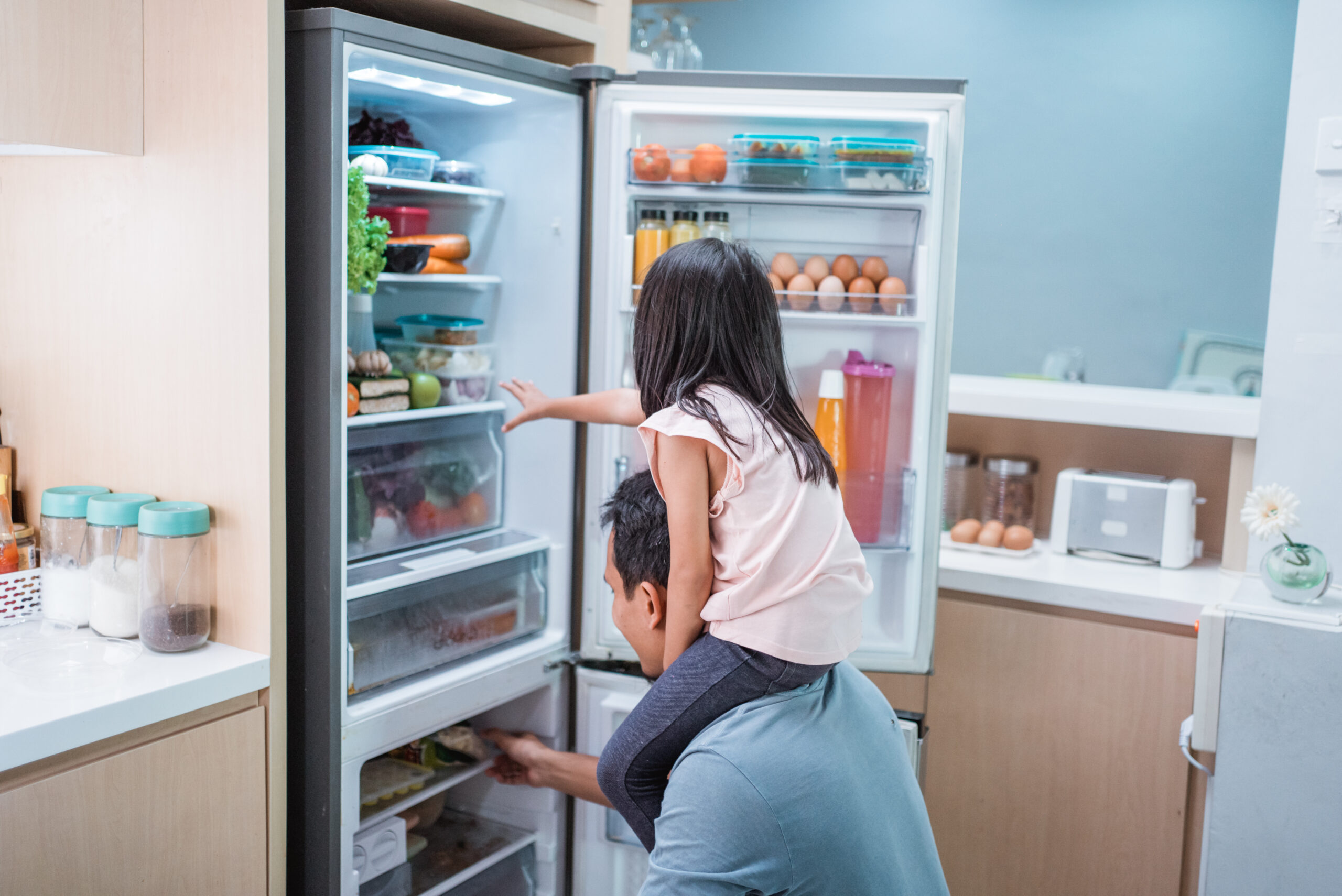 Young asian father and daughter open refrigerator at home looking for some food