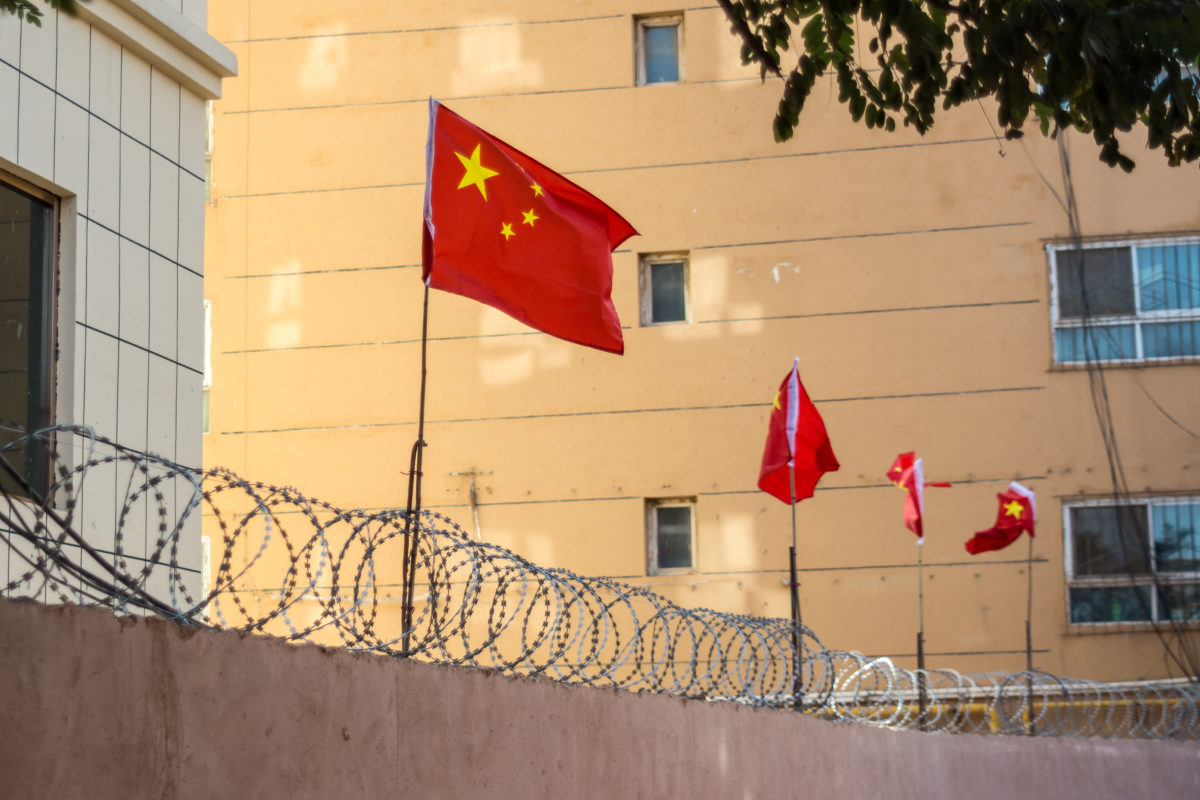 Chinese flags on barbed wired wall in Kashgar (Kashi), Xinjiang, China.