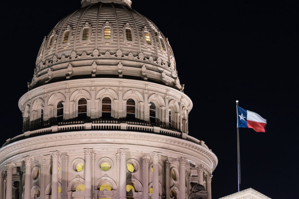 Flags blow in the wind after night falls on the state capital grounds in Austin