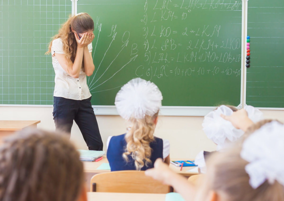 Teacher woman in stress or depression at school classroom, children or students driving her crazy.