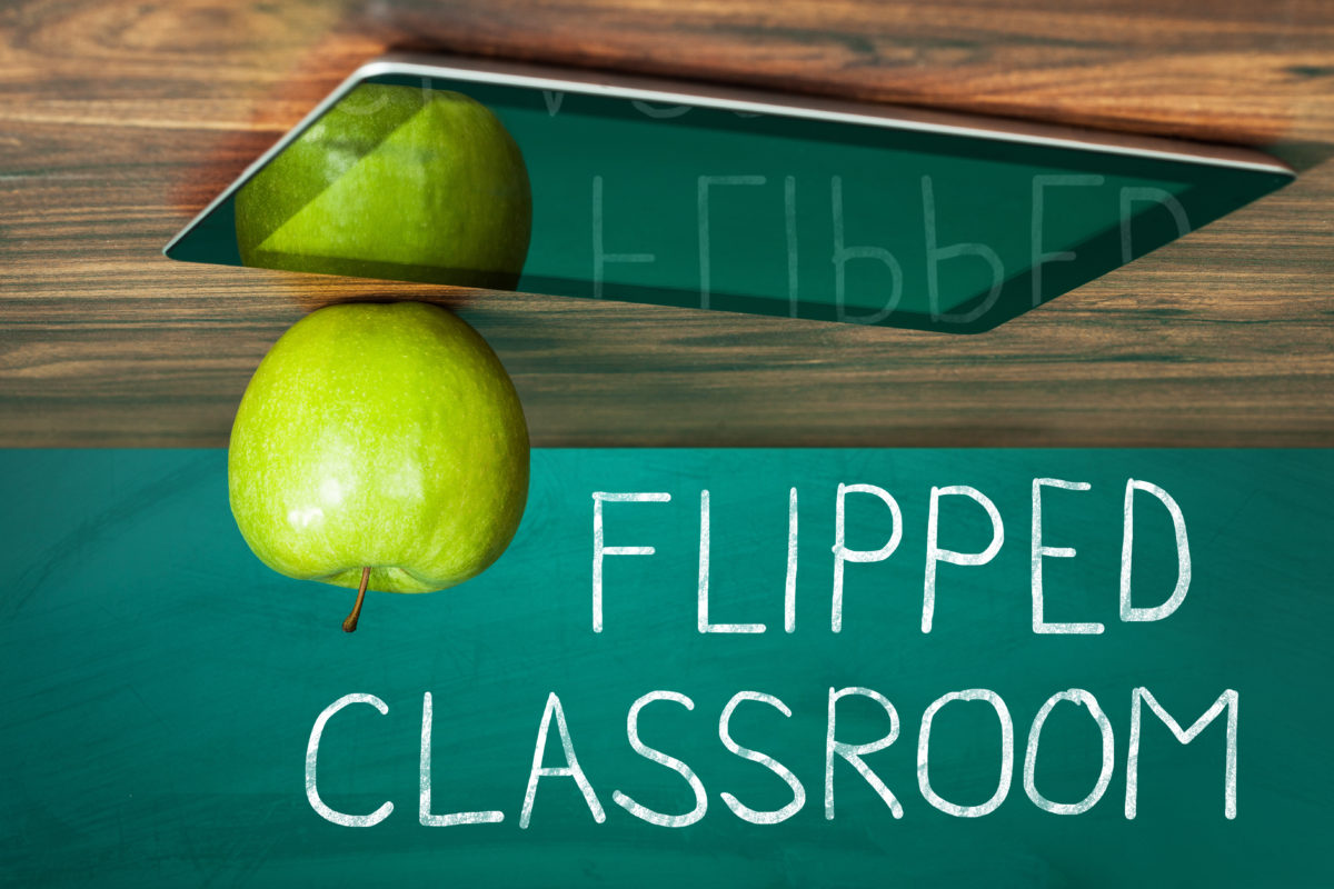 Flipped Classroom Concept On Blackboard With Apple And Digital Tablet On Wooden Table