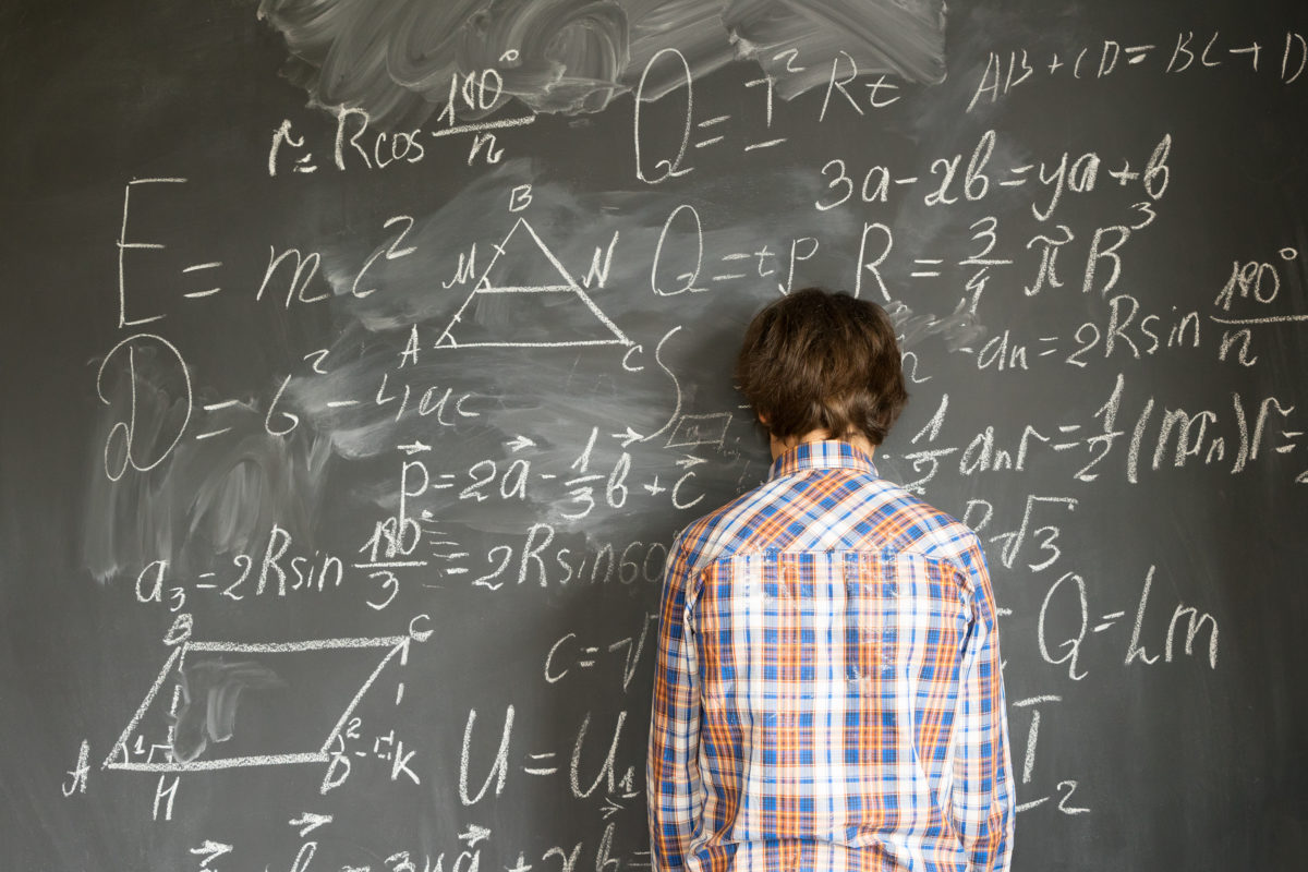 Teenageer Boy having trouble with complicated math formulas on black board