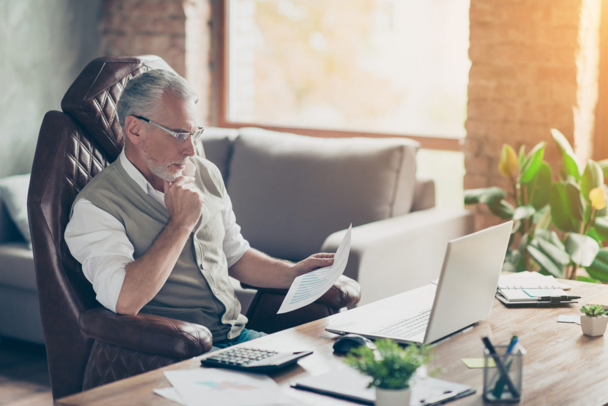 Plan profit paper cost debt credit bill success tax people armchair chair freelance company owner concept. Side profile view photo of serious pensive analyzing minded economist holding graphs in hand