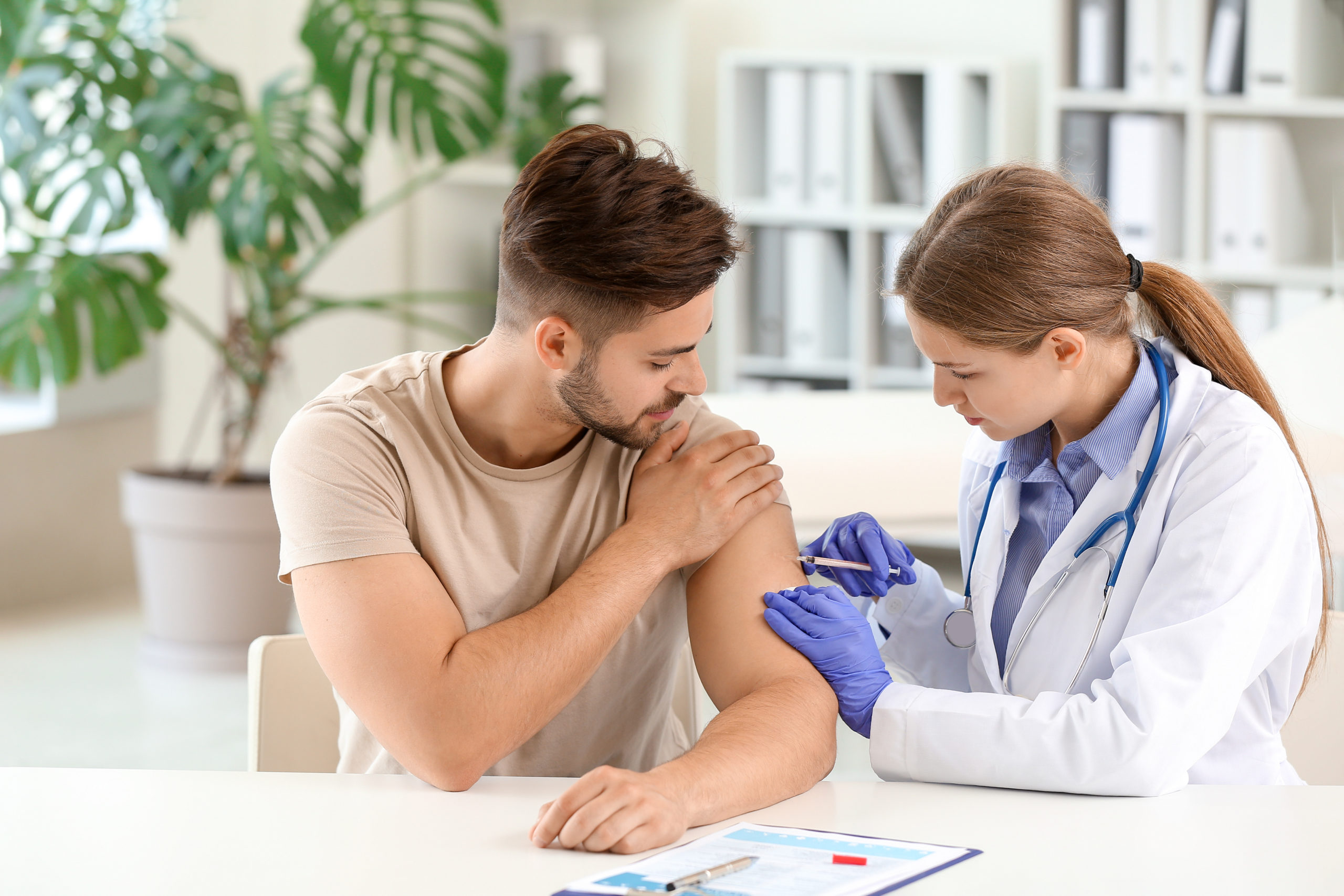 Doctor vaccinating young man in clinic