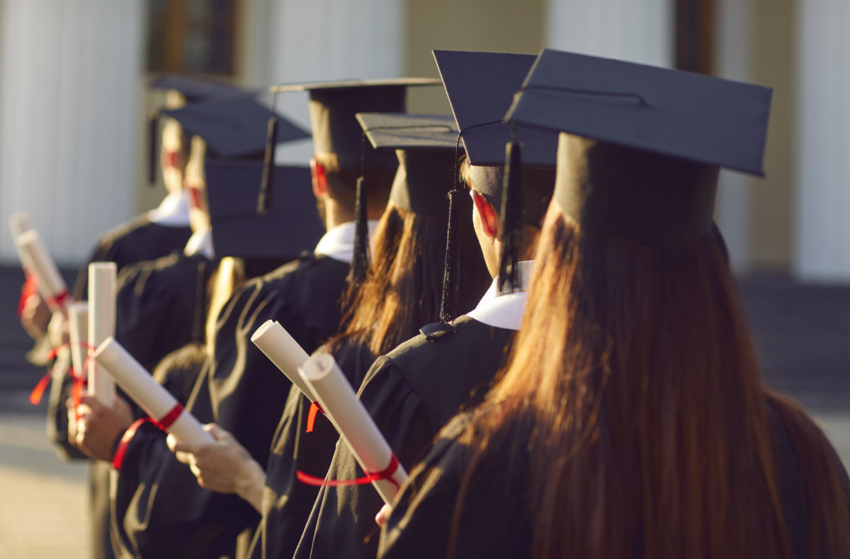 Group graduate.University graduates line up hold degree award in graduation ceremony rear view