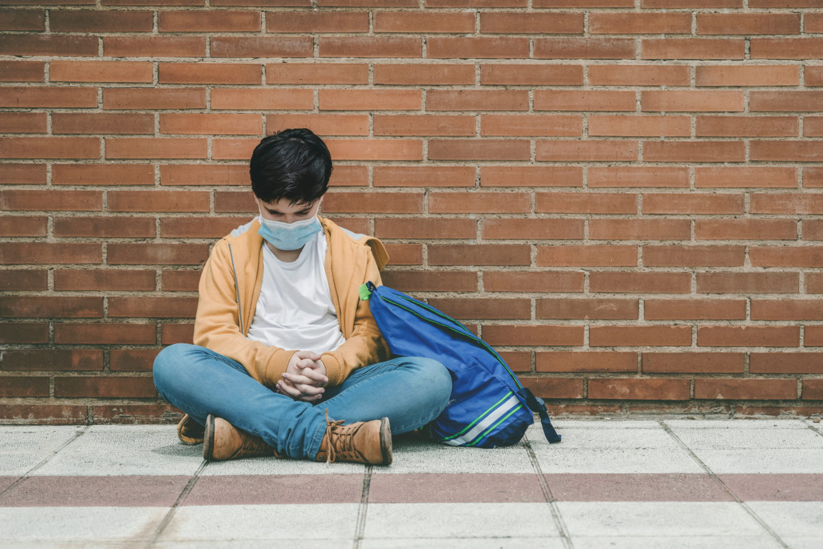 sad kid with medical mask and backpack