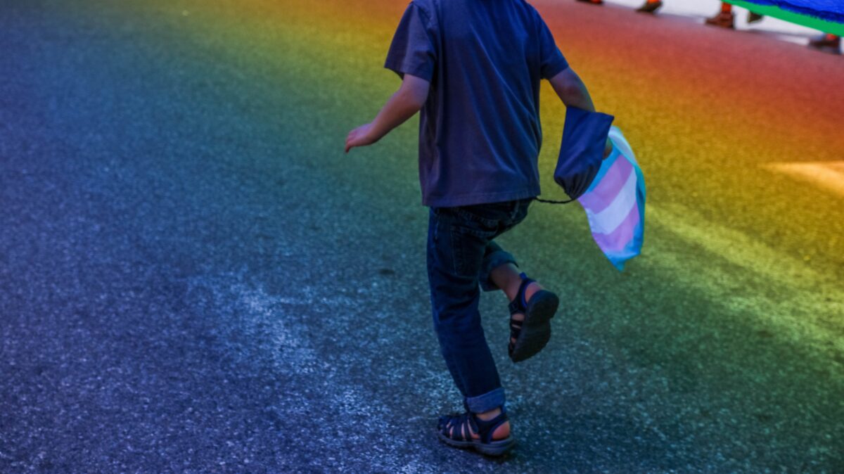 A child runs underneath the rainbow flag in Portland, Maine during the Pride Parade