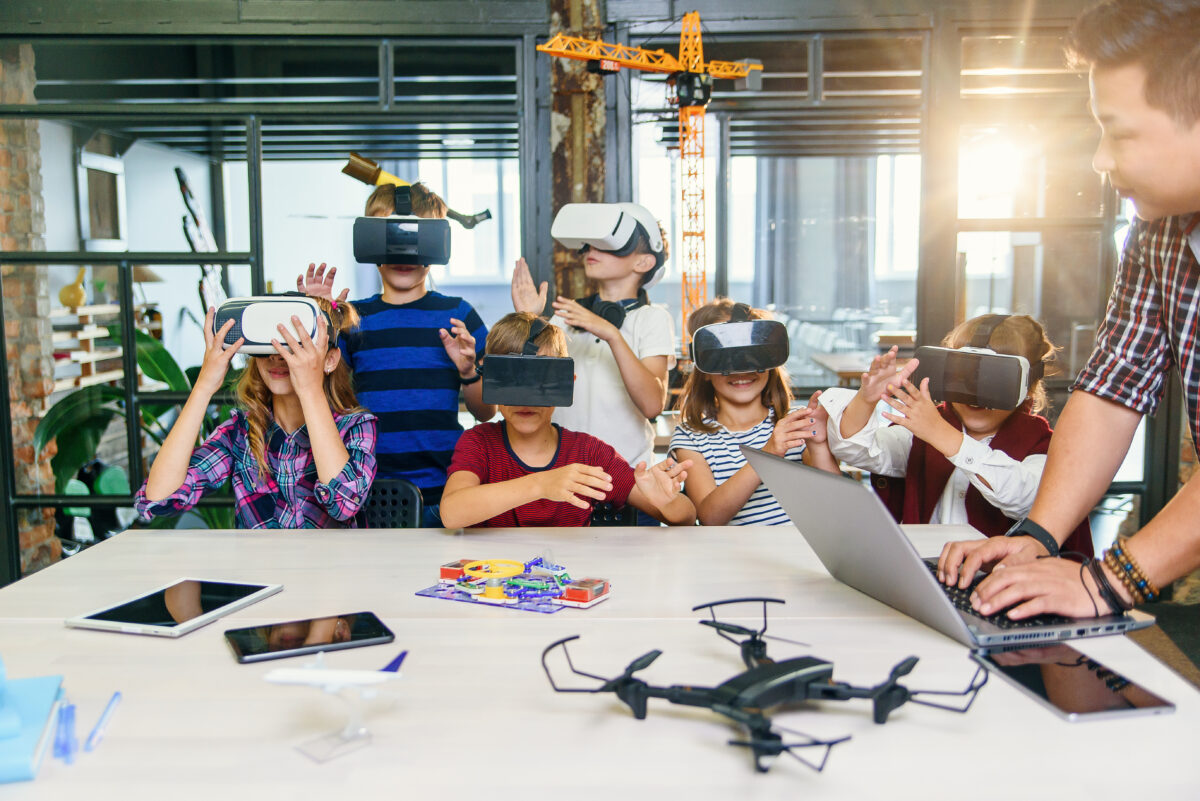 Group of young pupils of elementary school using virtual reality glasses during computer coding class.