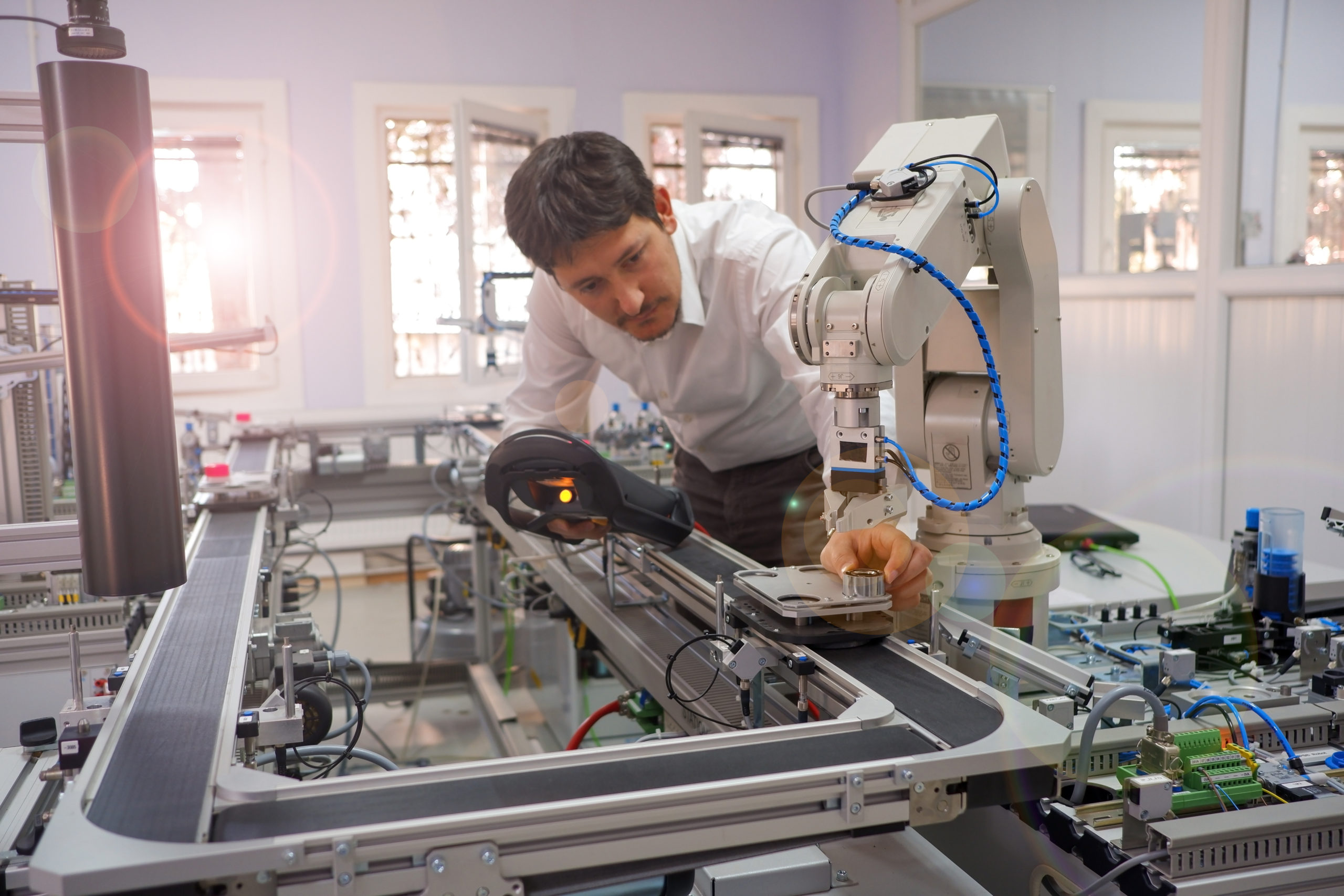 industry 4.0 concept: Man is holding product and teaching robot arm the points with control panel ( teach pendant ) on smart factory production line background. Selective Focus.