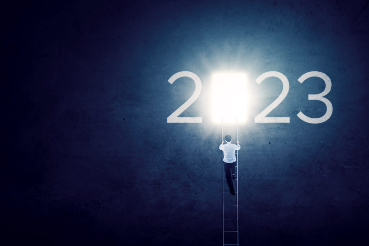 Man climbing a ladder toward a bright 2023 number