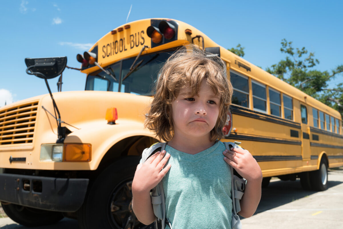 Sad boy front of a school bus. Child School concept. Education. Home education.