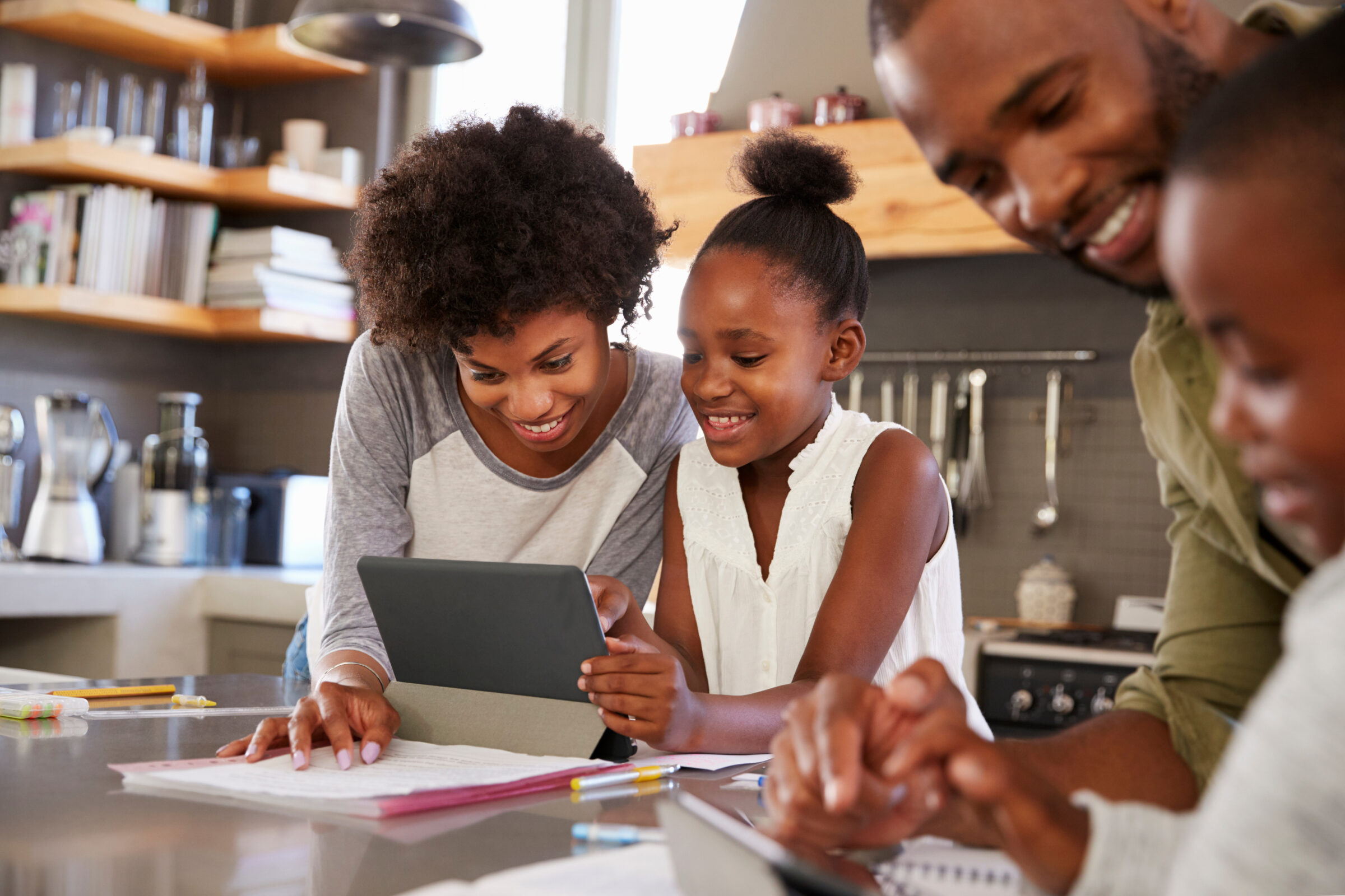 Parents Helping Children With Homework In Kitchen