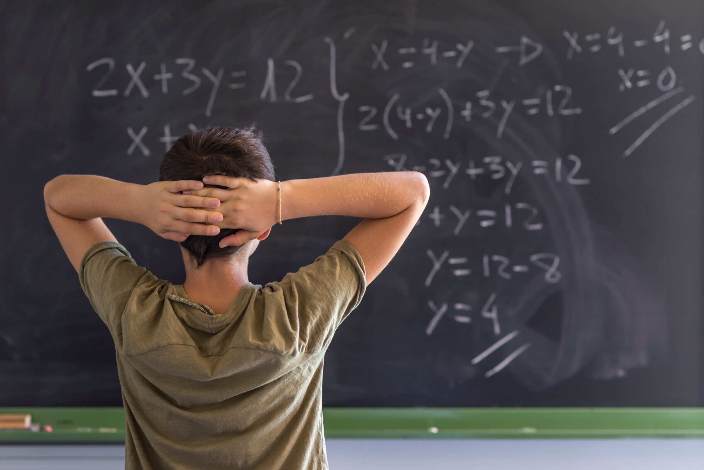 Schoolboy solving a problem on a blackboard.