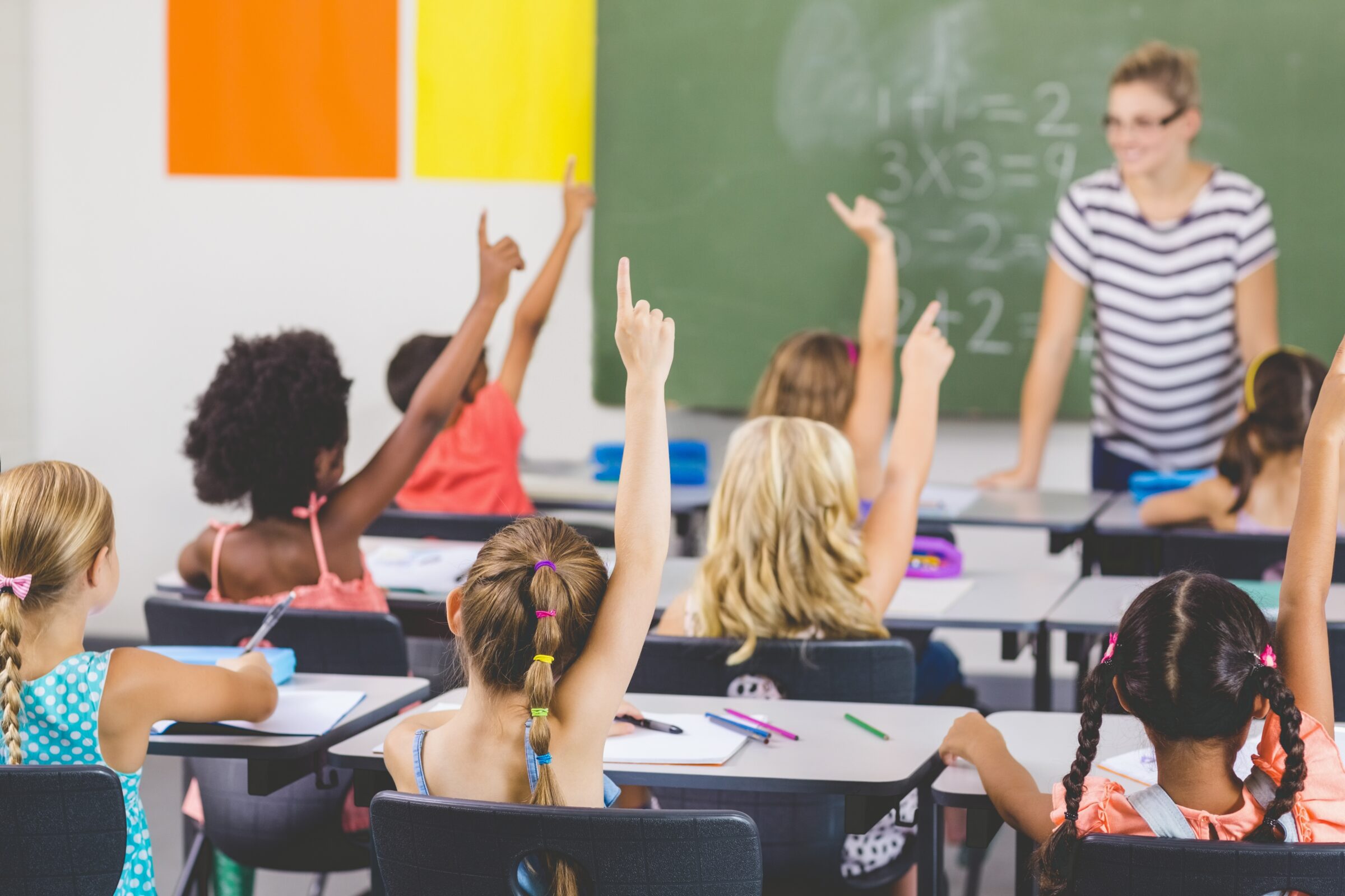 School kids raising hand in classroom