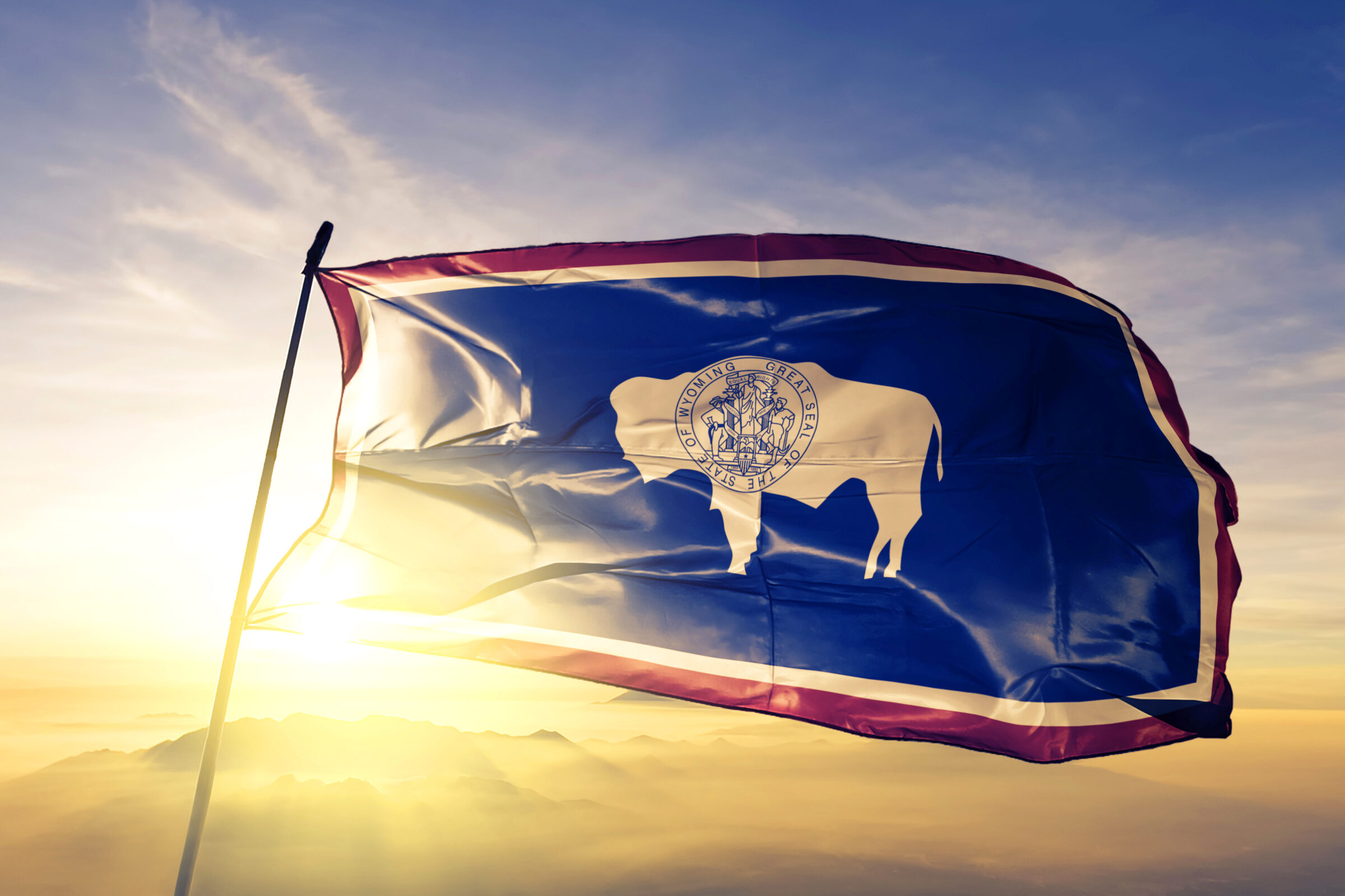 Wyoming state of United States flag waving on the top sunrise mist fog