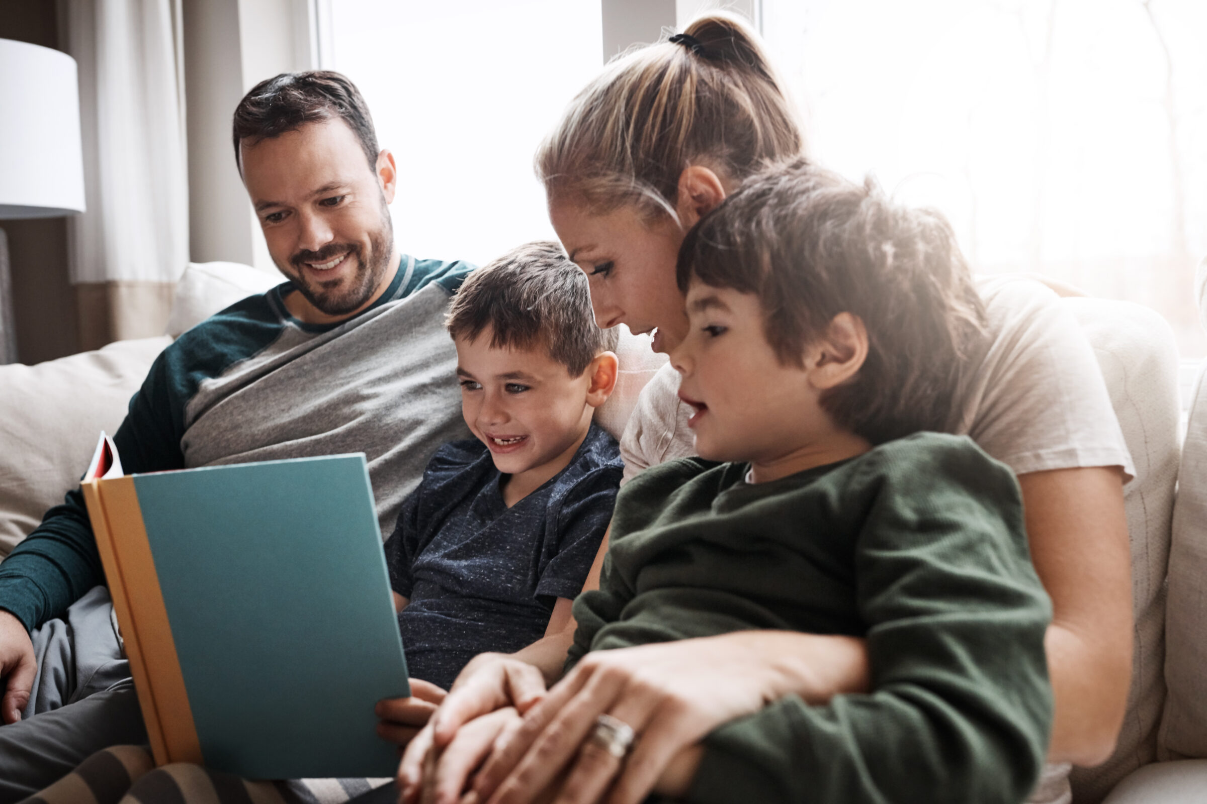 Relax, children and parents reading a book for bonding, fun and quality time. Knowledge, information and boys excited about learning a story together on the lounge sofa with their mother and father